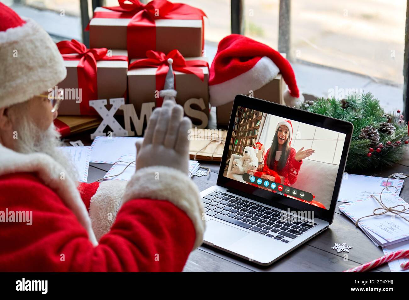 Santa Claus talking to child on laptop video call open present sit at table. Stock Photo