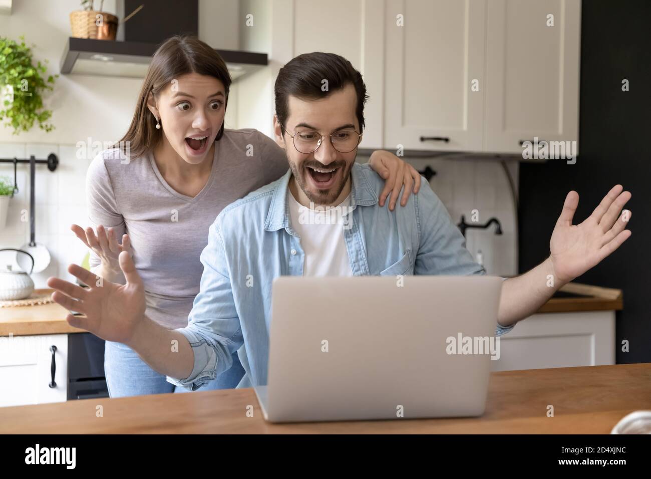 Shocked happy young family couple looking at computer screen. Stock Photo