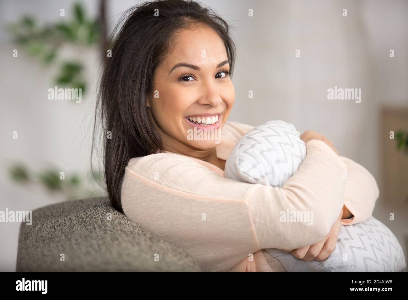 happy woman hugging a pillow sitiing on sofa Stock Photo Alamy