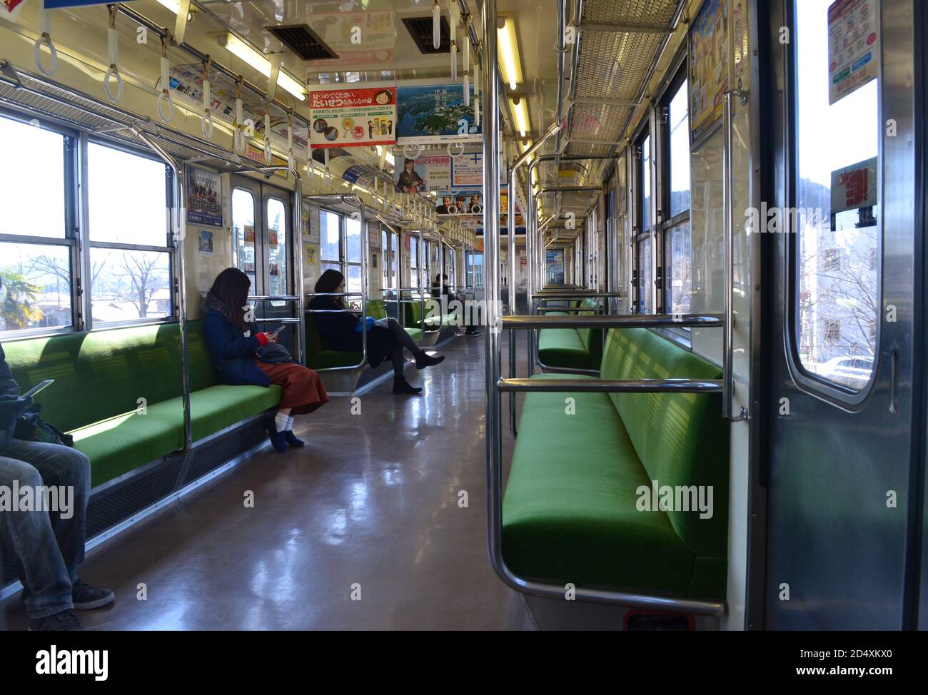Itasbashi, Japan-2/25/16: Inside a semi-empty local Japanese train traveling from Itabashi; the passengers sit far apart on the green seating. Stock Photo