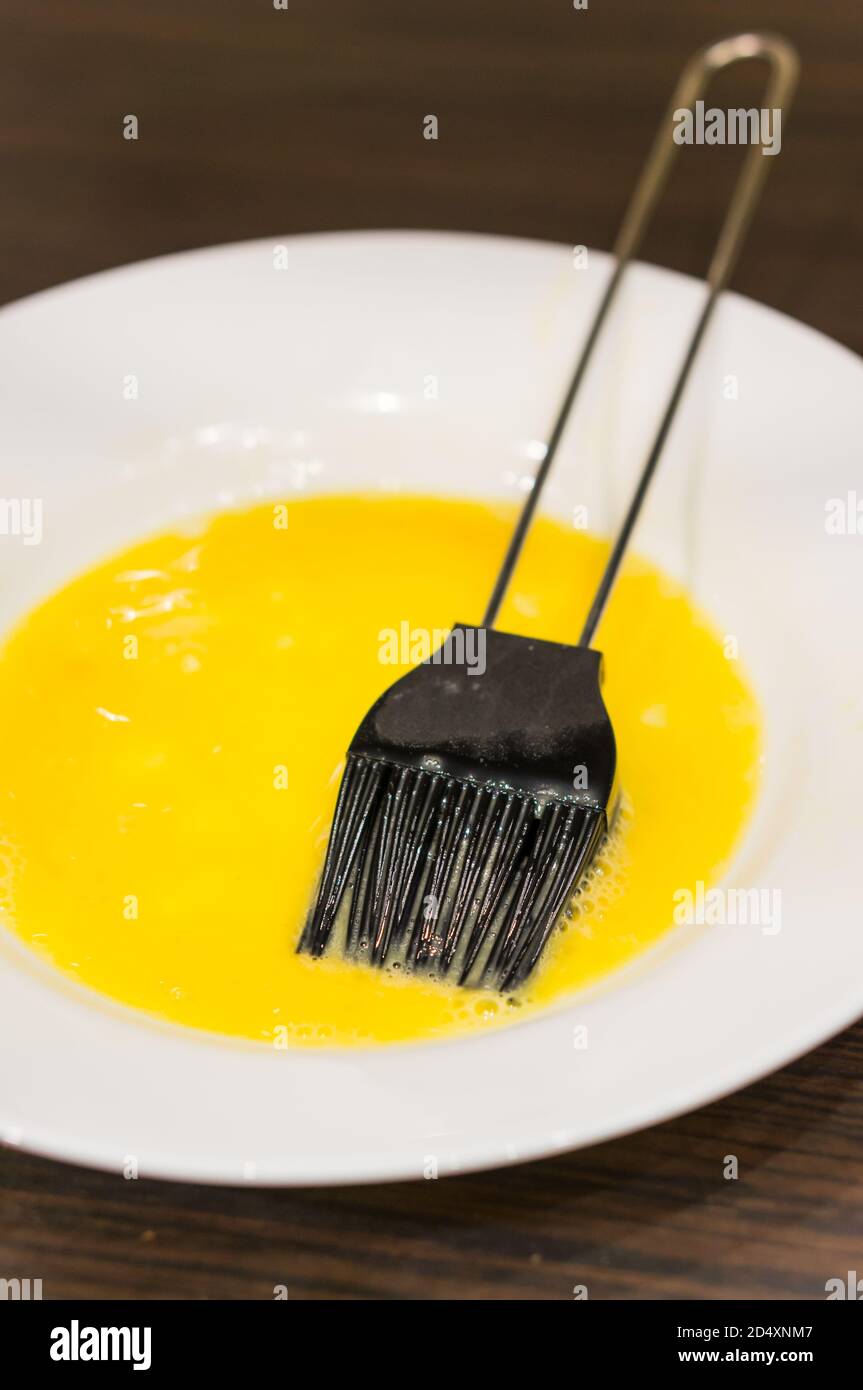 Vertical Shot of an Egg Wash in a Plate with Black Pastry Brush