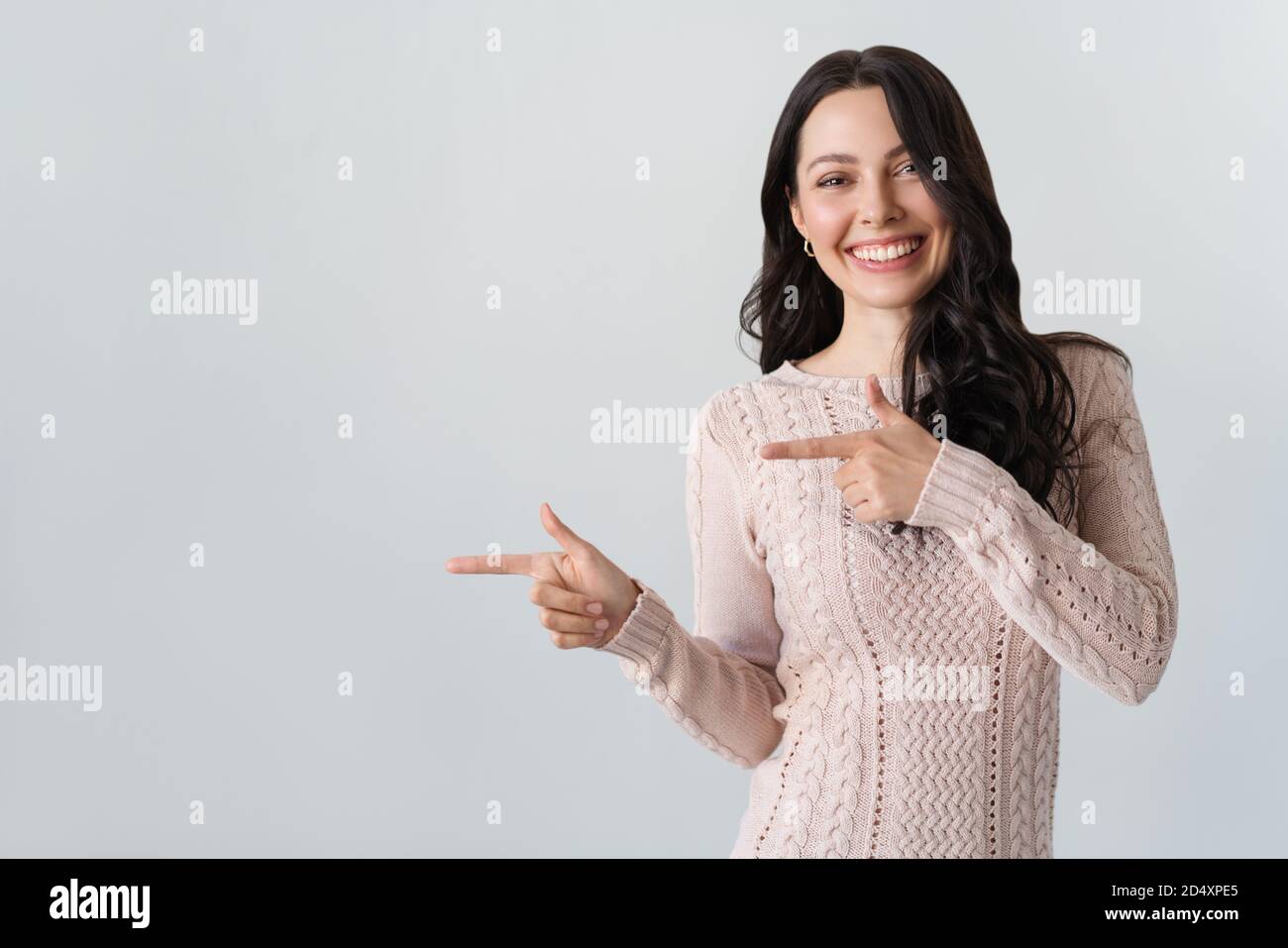 Young woman smiling and gesturing to copy space. Stock Photo