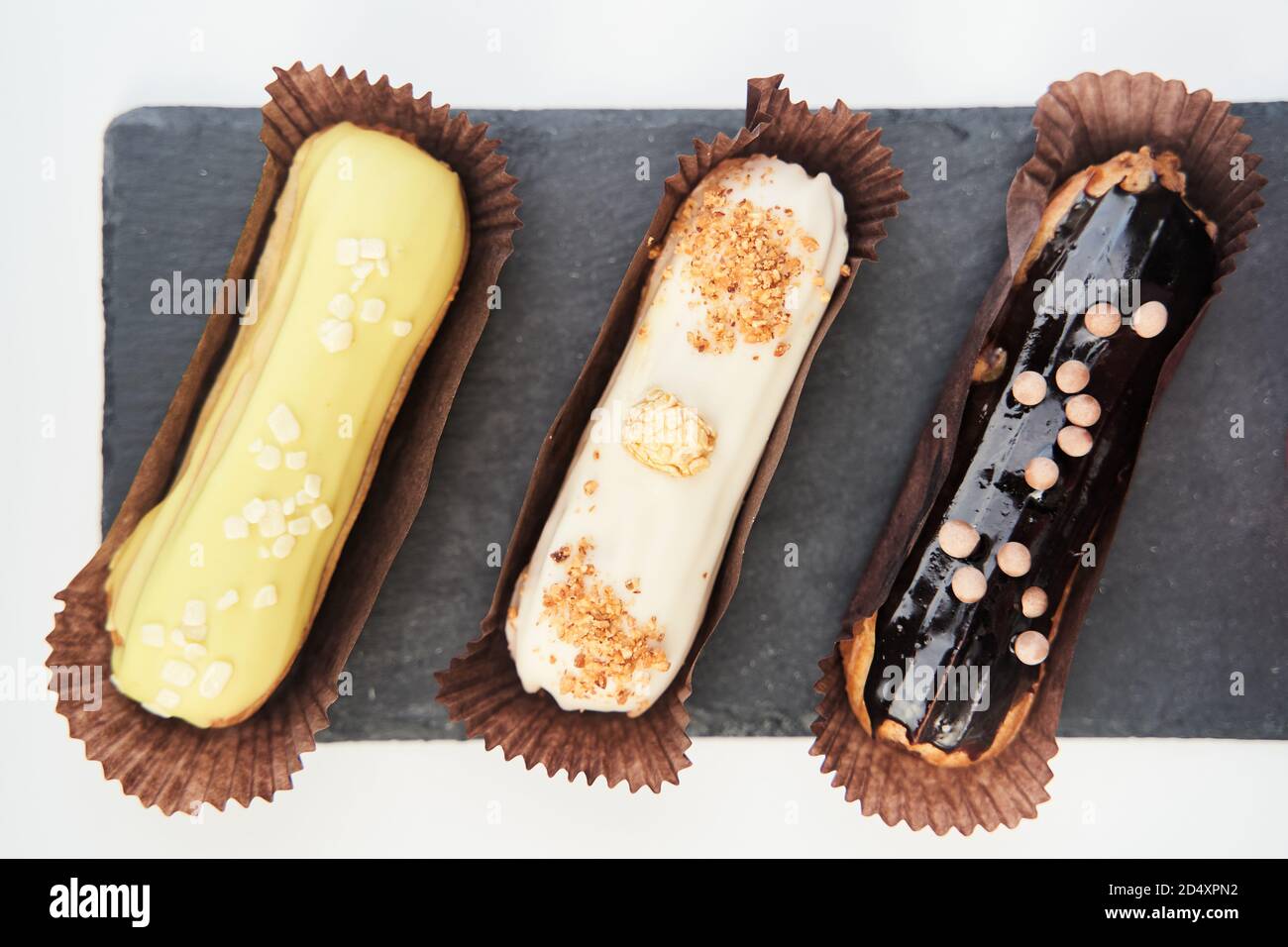 Three eclairs on a black tray top view Stock Photo