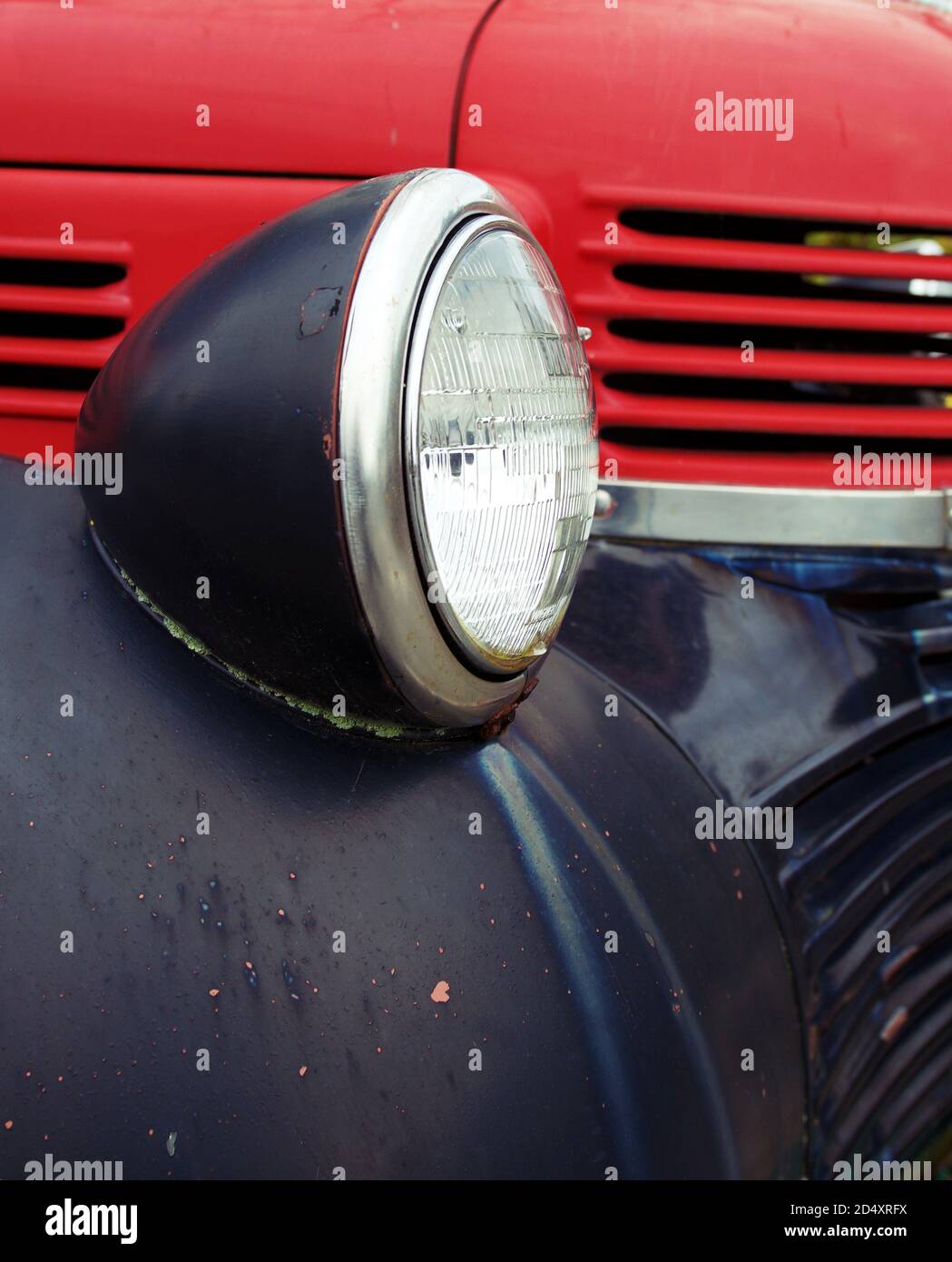 Headlight and part of hood of an old red and black vintage car Stock