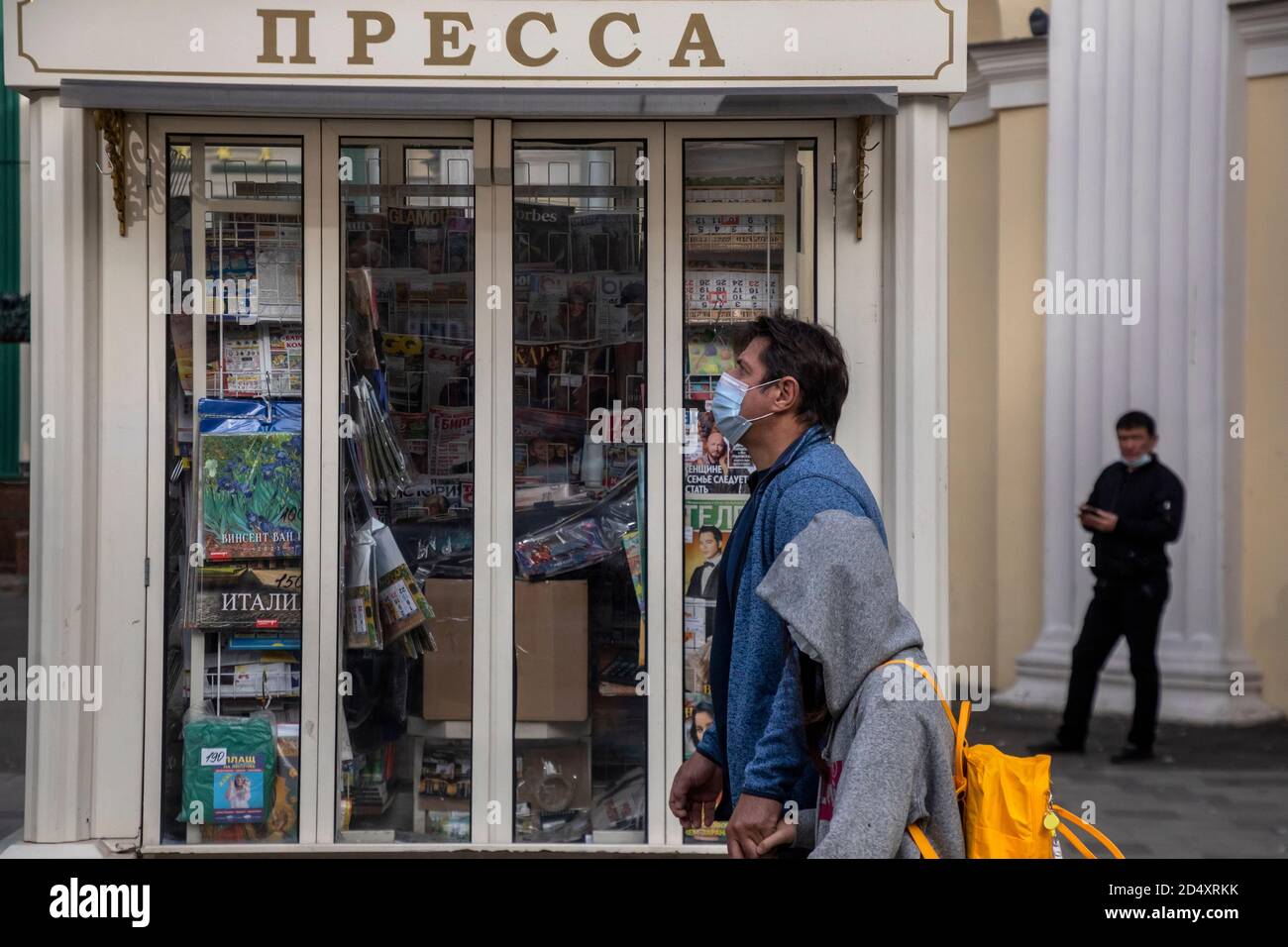 Moscow, Russia. 11th of October, 2020 People wearing protective face mask walk in the background of Russian newspapers and a street newsstand on the central street of Moscow city during the novel coronavirus COVID-19 pandemic in Russia Stock Photo