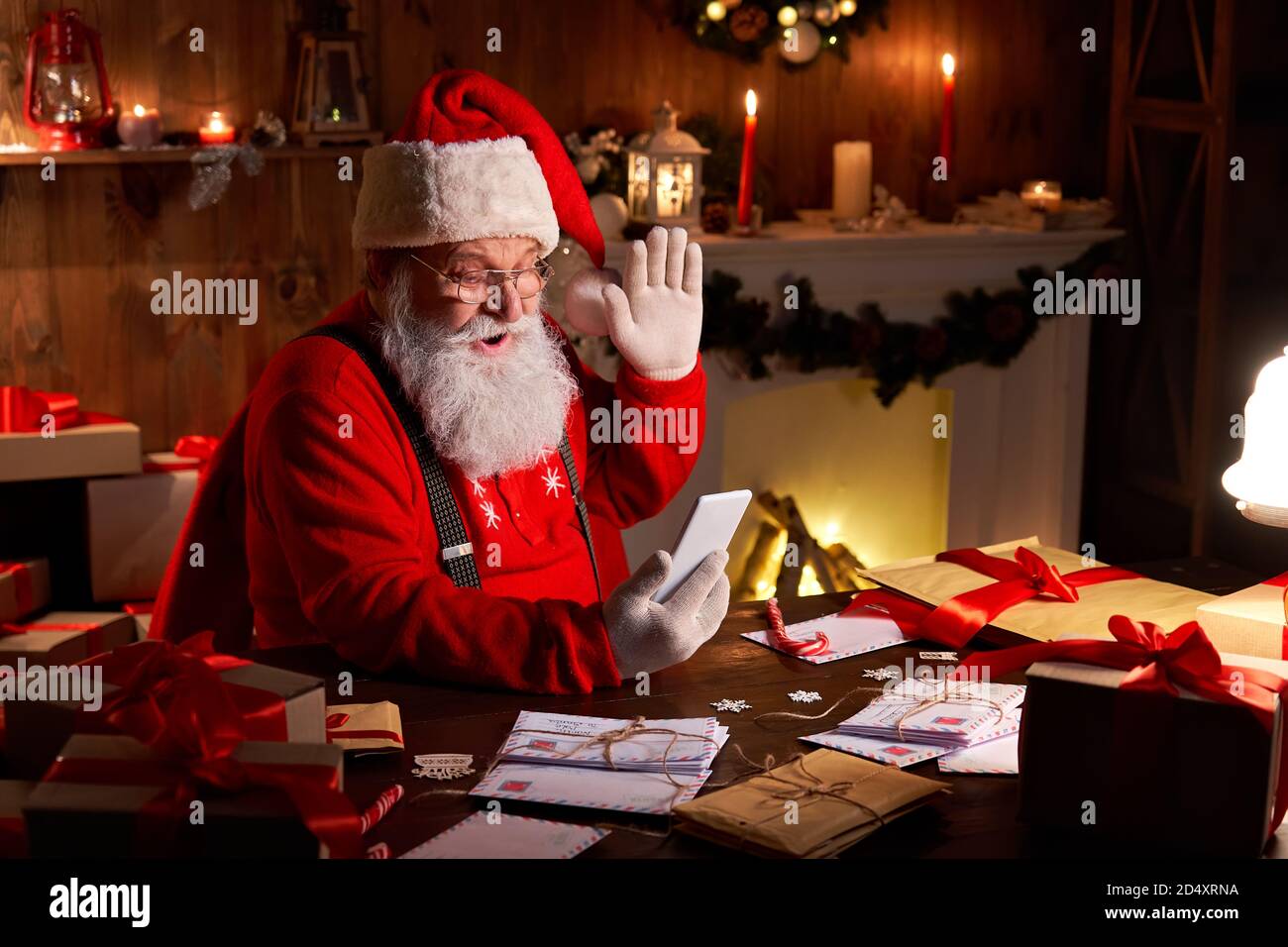 Santa Claus video calling child on smartphone sitting at home table. Stock Photo