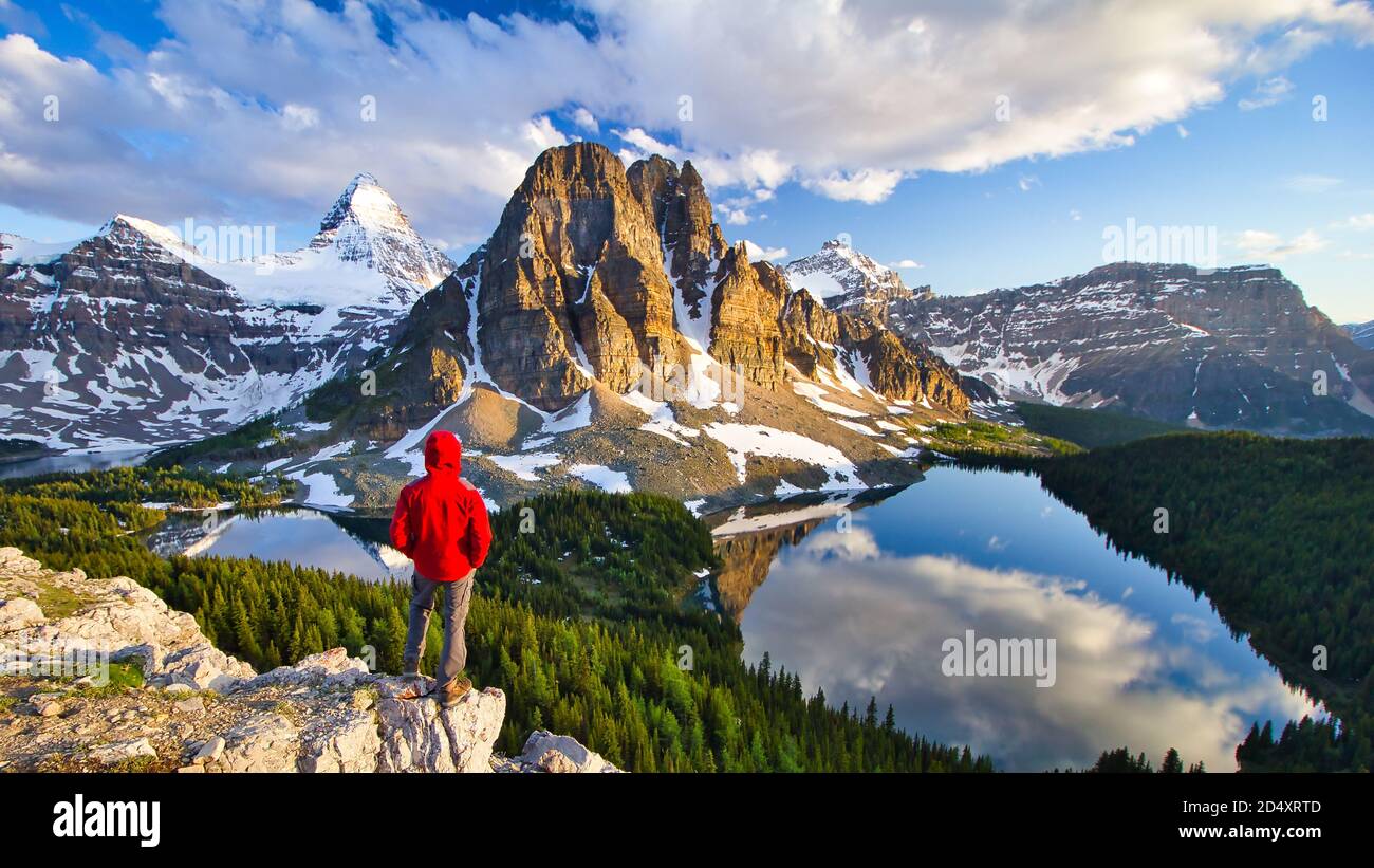 Hiker person overlooking Mount Assiniboine with Magog, Sunburst and Cerulean lakes as seen from Nub Peak, British Columbia, Canada Stock Photo