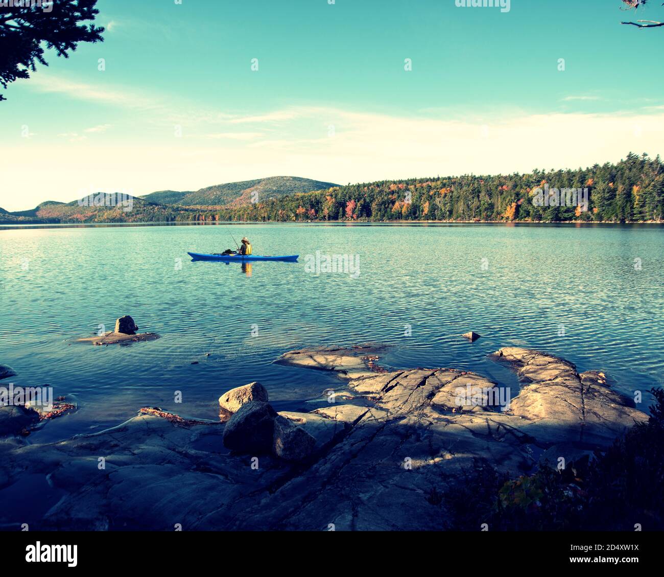 Person kayaking across Eagle Lake in Acadia National park Maine, during Fall day. Stock Photo