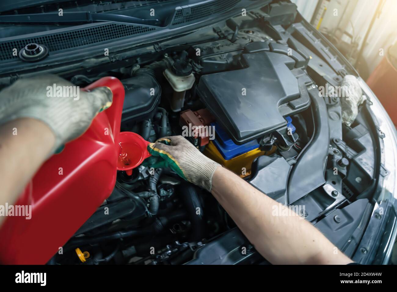 Pouring new engine oil from canister into motor funnel at car service