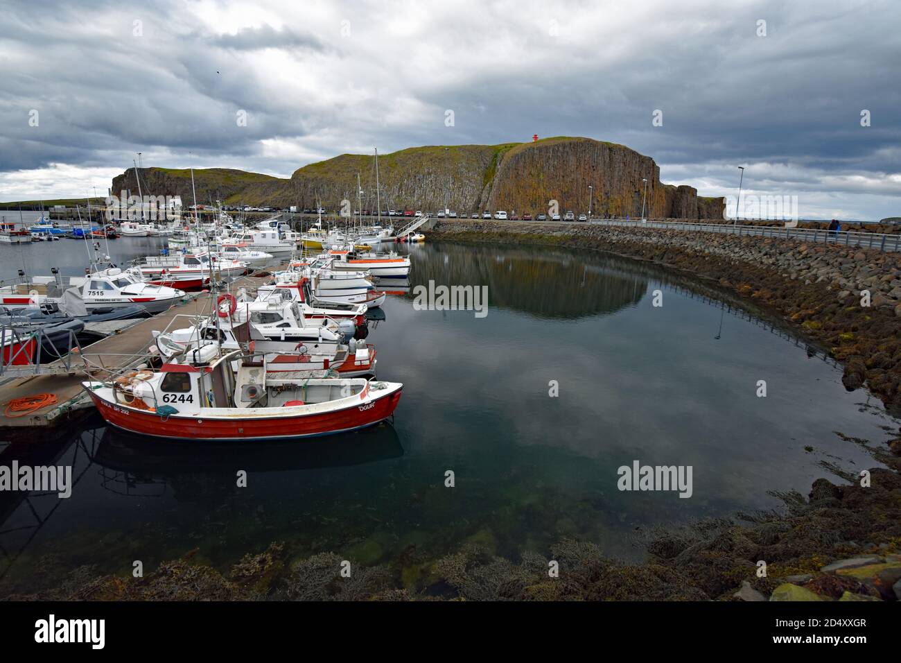 Stykkishólmur Harbour with Sugandisey cliff and lighthouse on top. Snaefellsnes Peninsular, Iceland. Small boats are tied to the floating pontoon. Stock Photo