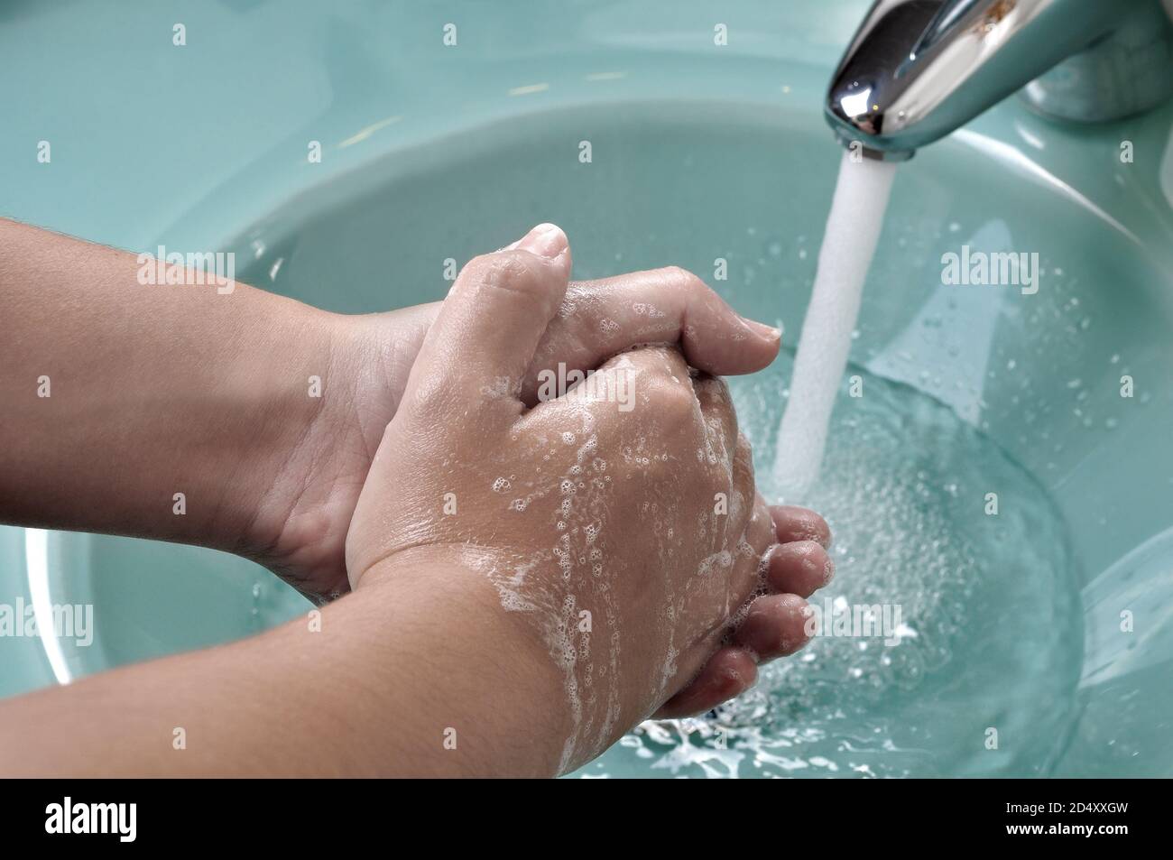 Hands being washed in a green sink during the coronavirus pandemic Stock Photo