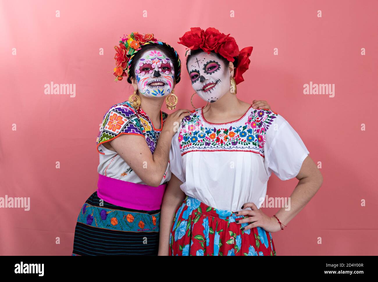 Two young women disguised as catrinas with Mexican costumes, posing with a  plain background Stock Photo - Alamy