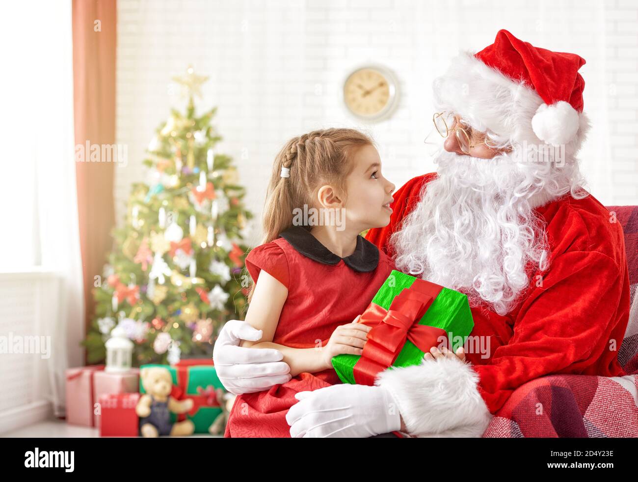 Santa Claus giving a present to a little cute girl Stock Photo - Alamy
