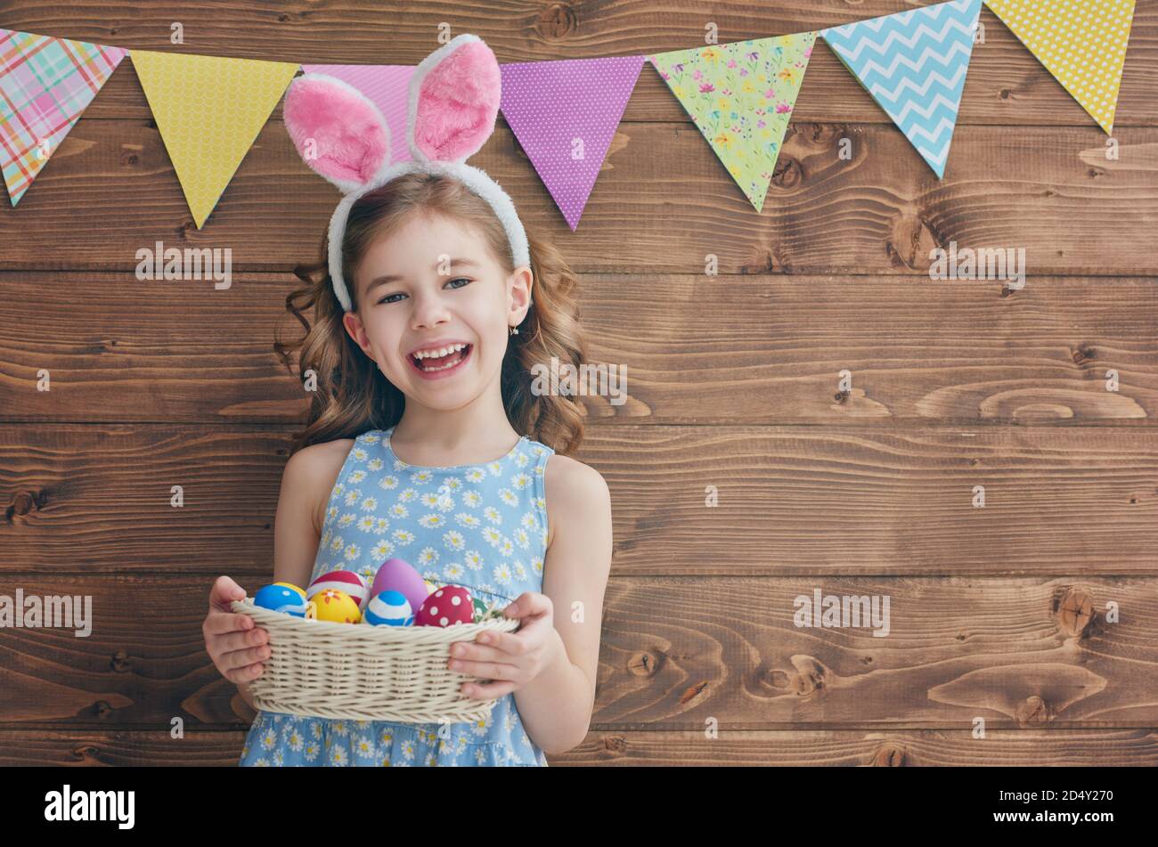 Cute little child wearing bunny ears on Easter day. Girl holding basket ...