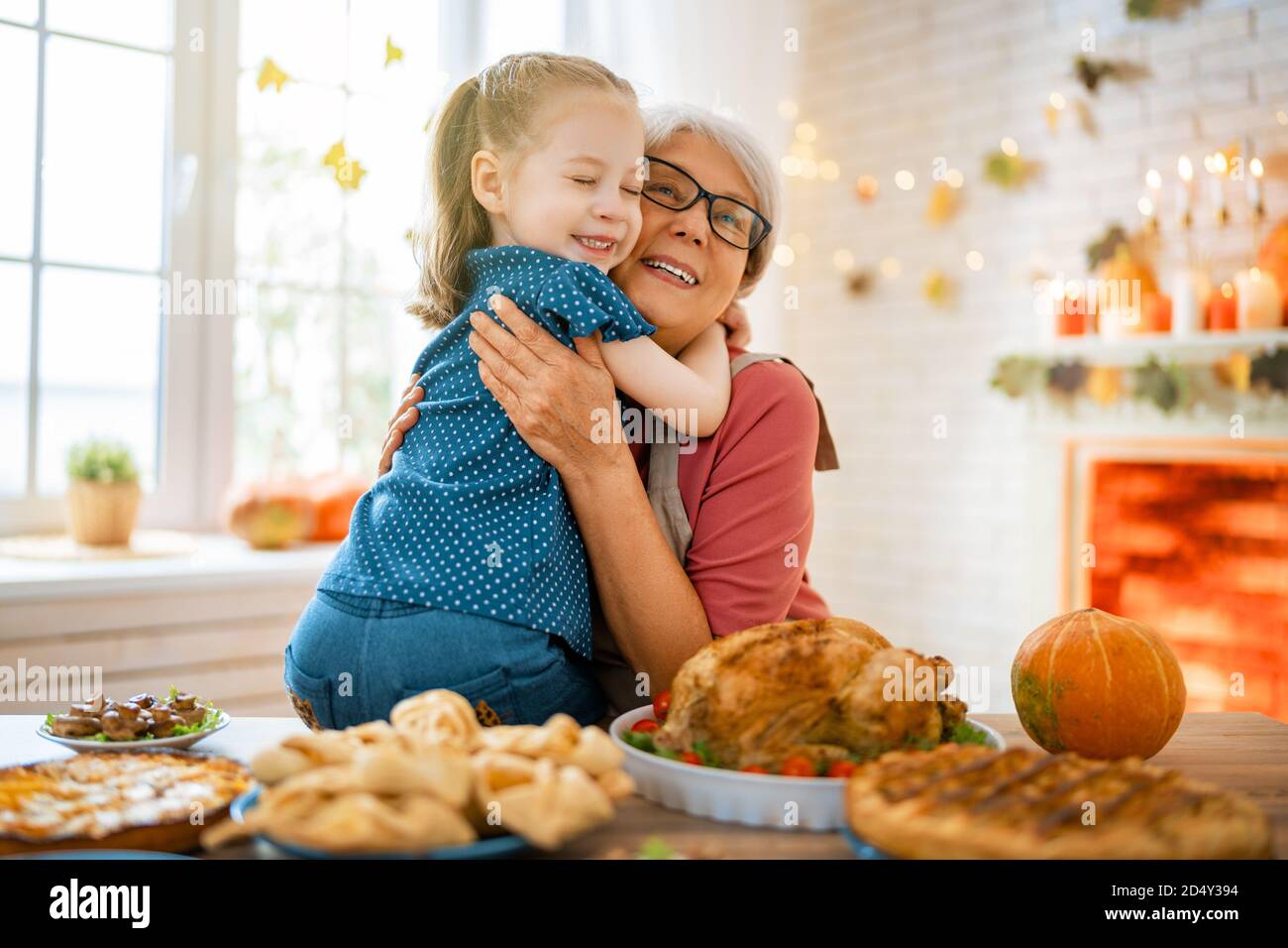 Happy Thanksgiving Day Autumn Feast Family Sitting At The Table And   Happy Thanksgiving Day! Autumn Feast Family Sitting At The Table And Celebrating Holiday Traditional Dinner Grandmother And Granddaughter 2D4Y394 