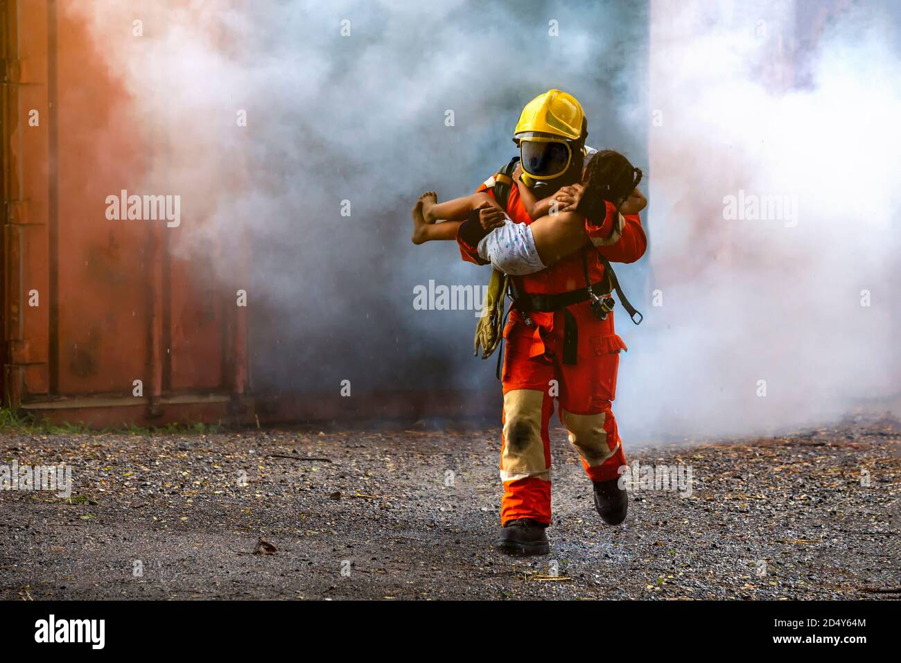 Firefighter rescue, Fireman walking out from burning building and hold save a child in his arms from fire incident. Stock Photo