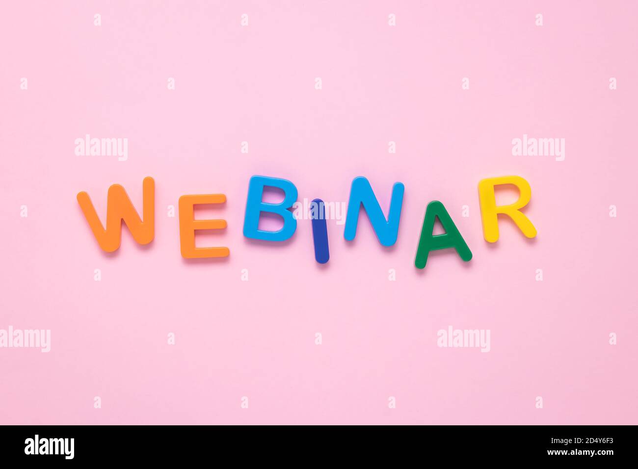 Single word - webinar. Text from colorful plastic letters on a pink paper background. The message on poster. Multicolor inscription on the banner. The Stock Photo