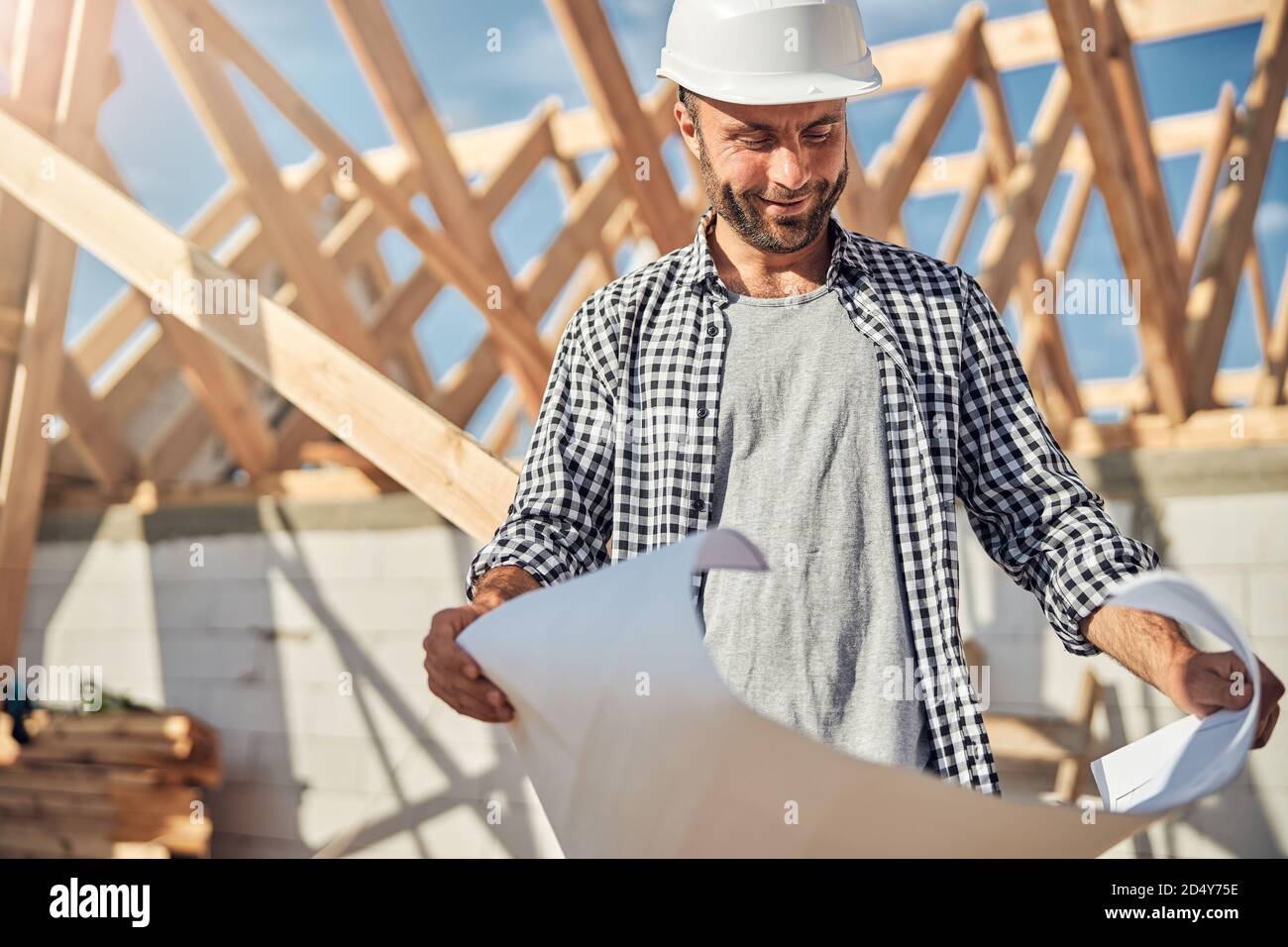 Gladsome engineer looking at a building plan on paper Stock Photo - Alamy