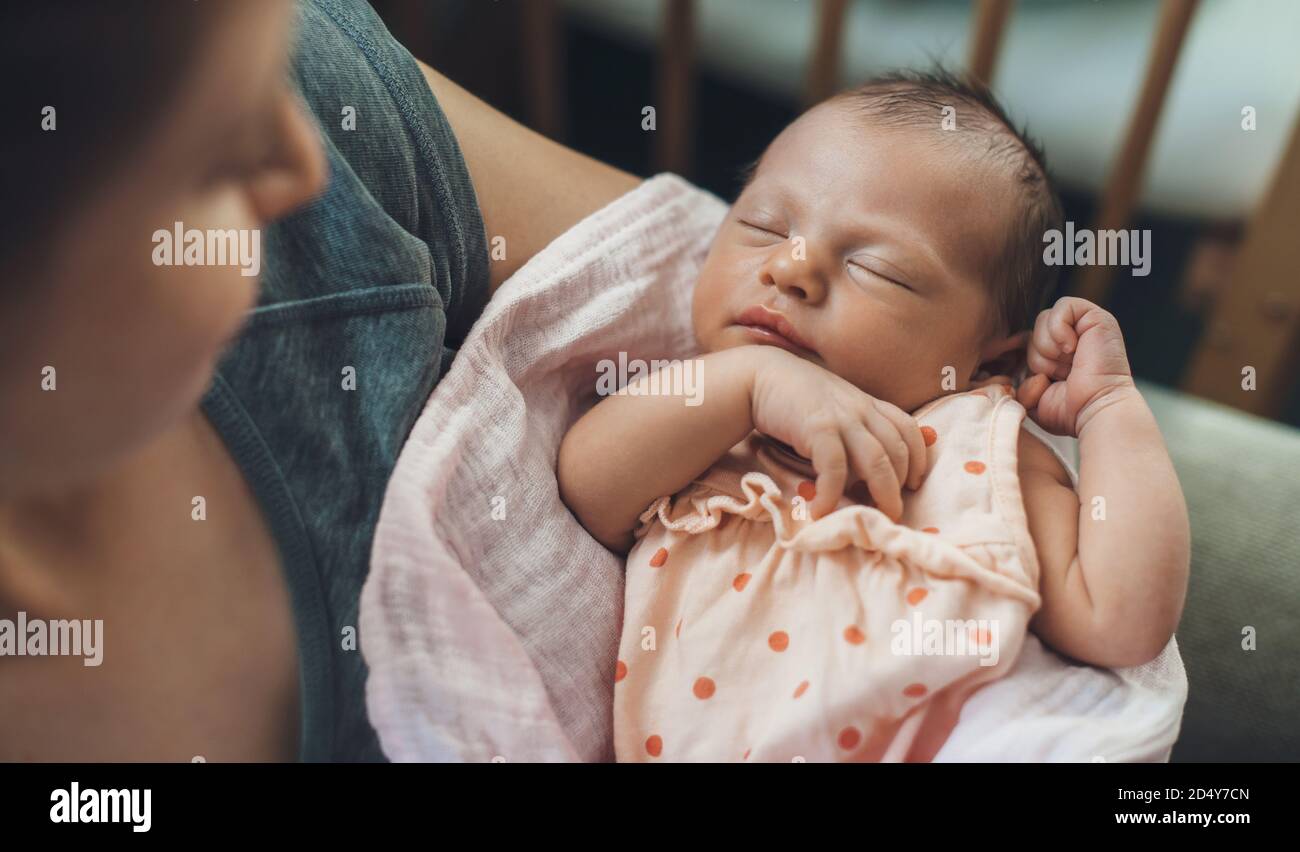 Newborn baby sleeping in safety while mother is holding and smiling at