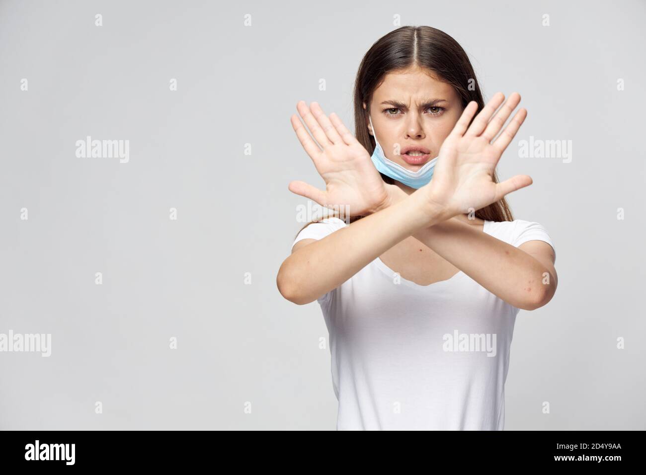 woman in medical mask holding crossed arms in front of her white t ...