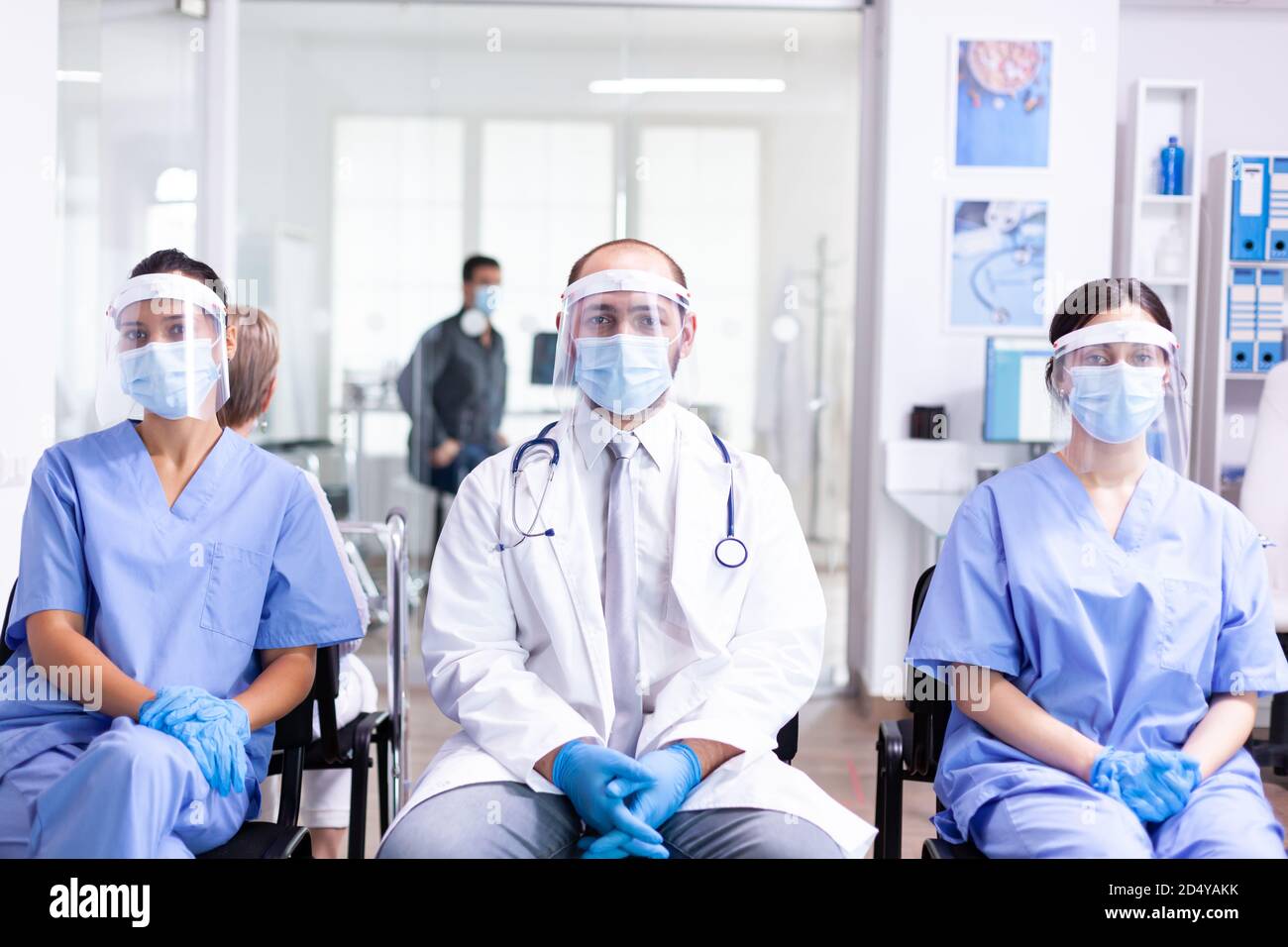 Medical staff in clinic waiting area wearing face mask protection against coronavirus outbreak as safety precaution. Medic wearing stethoscope. Stock Photo