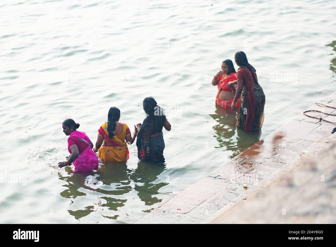 December 17 2019 Varanasi, India. A group of Indian women perform a sacred ablution in the Ganges river. Top view from the back. Stock Photo