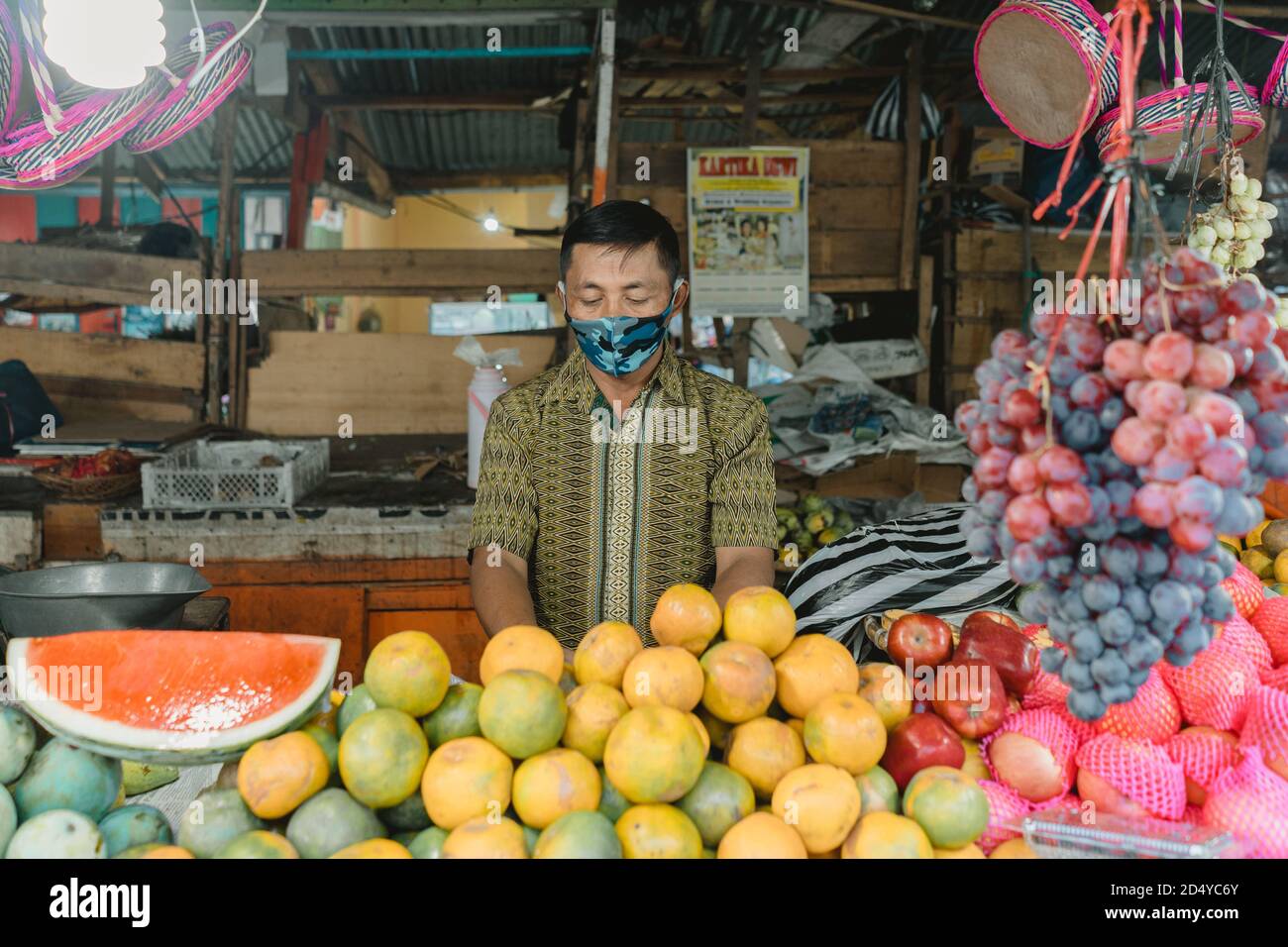 Salatiga, Indonesia - June 11, 2020: A fruits seller wears scuba mask for preventing the spread of coronavirus. Stock Photo