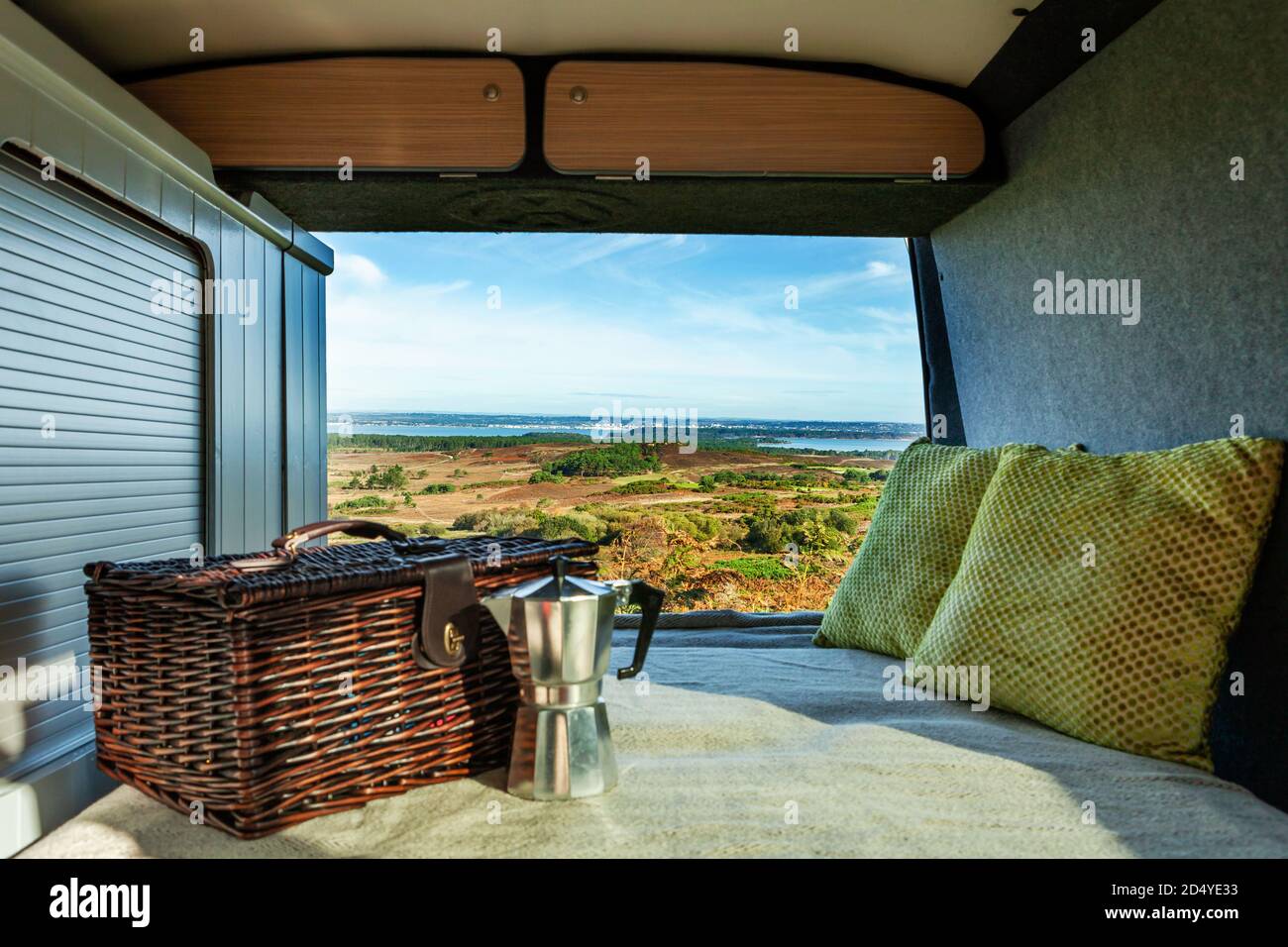 Taken from a camper van with a hamper, stovetop coffee maker and cushions, overlooking the view at Poole harbour, on a bright Autumn day. Stock Photo