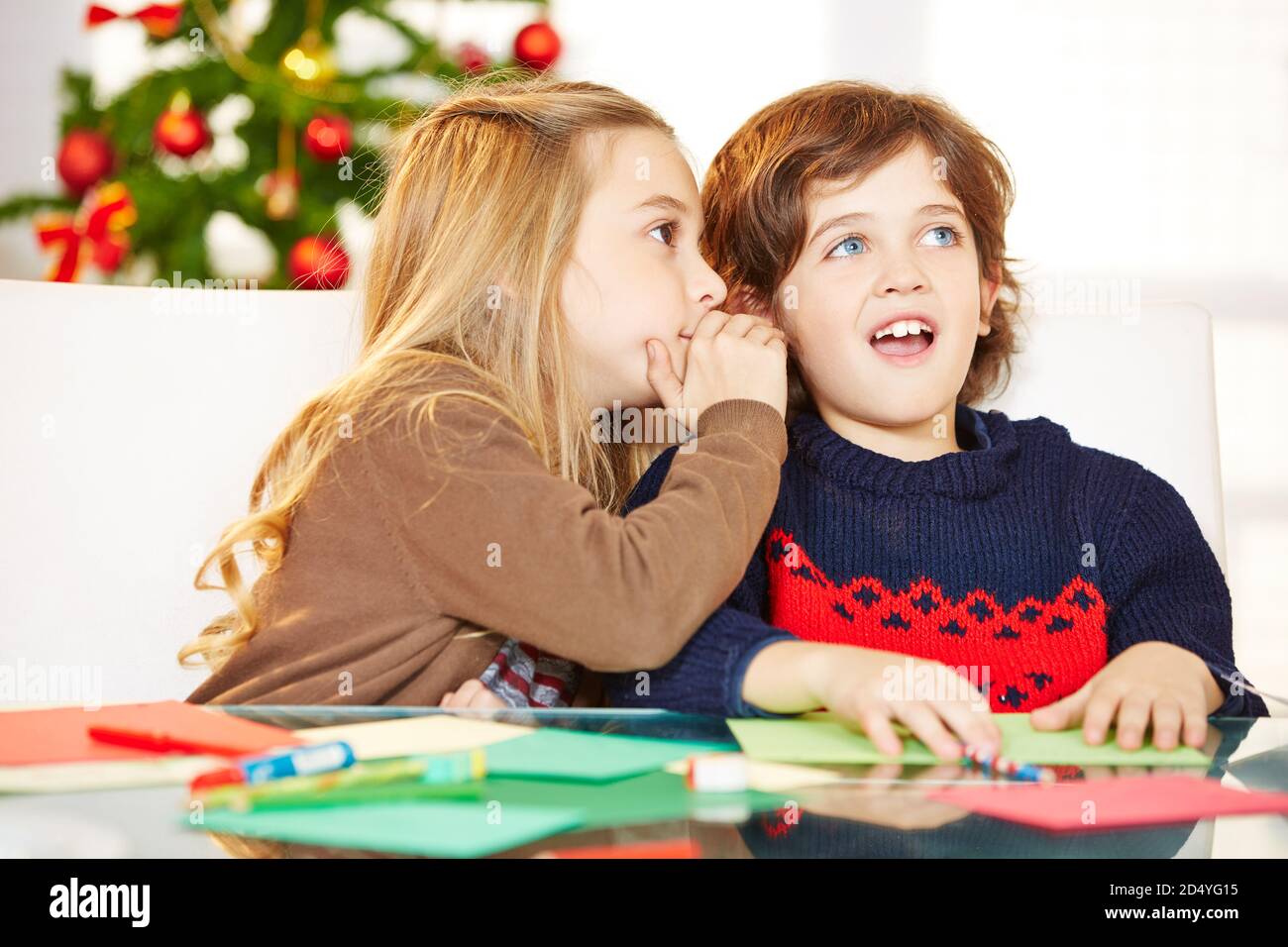 Girl whispers boy a secret in Christmas ear Stock Photo