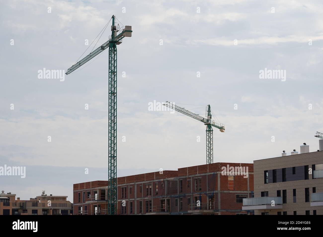 Low angle shot of tower cranes against a cloudy sky Stock Photo - Alamy