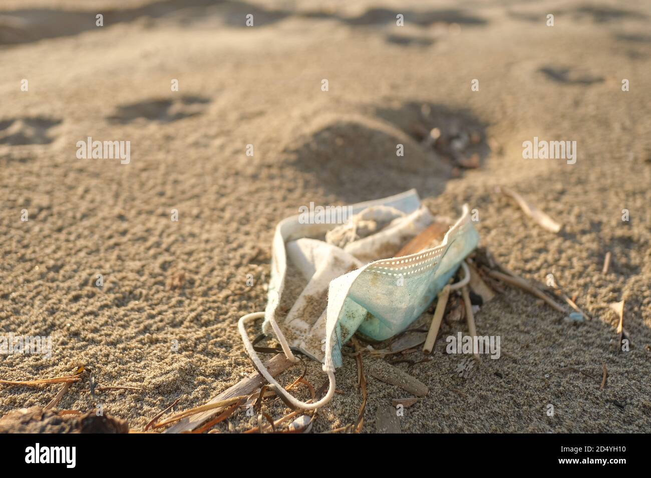 Dirty used surgical face mask discarded on sea coast ecosystem,covid19 pandemic disease pollution effects Stock Photo