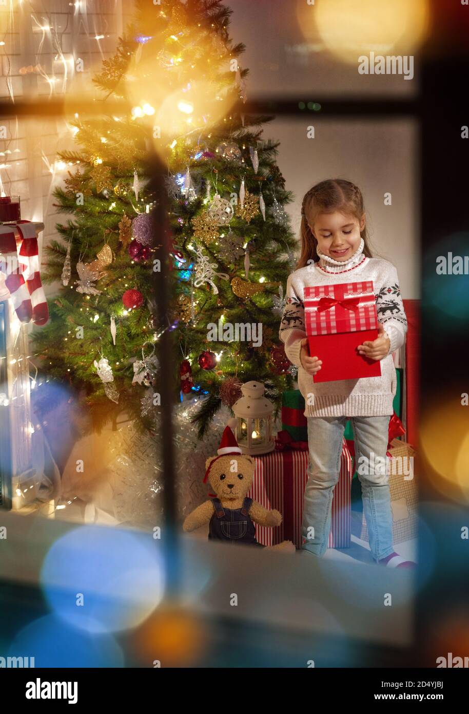 Cute little girl holding Christmas gift Stock Photo - Alamy