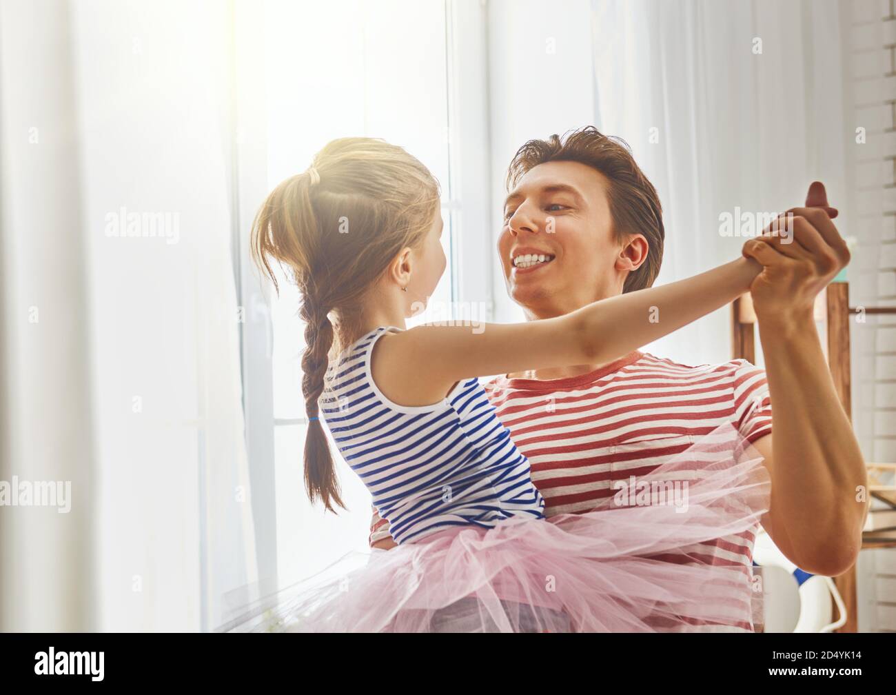 Happy father's day! Dad and his daughter child girl are playing, smiling and dancing. Family holiday and togetherness. Stock Photo