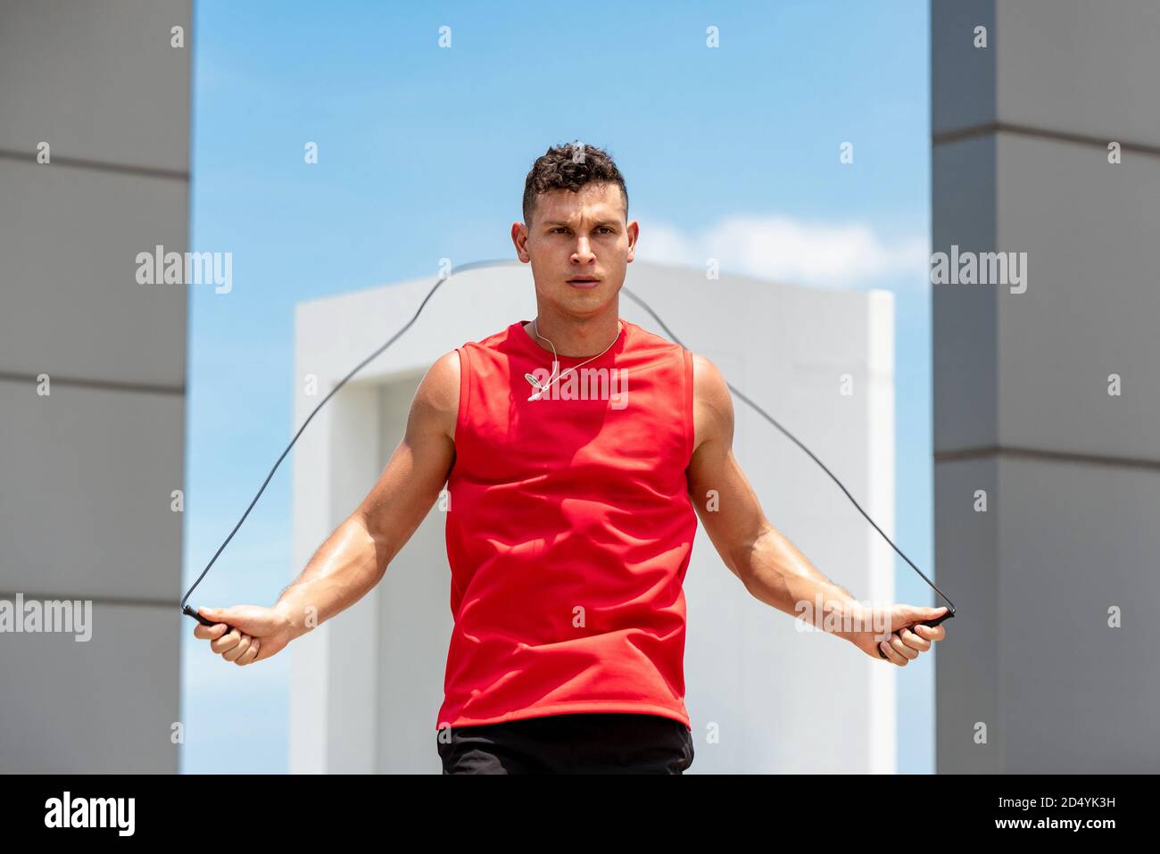 Handsome fit Caucasian athlete doing jump rope for daily morning cardio exercise on building rooftop Stock Photo