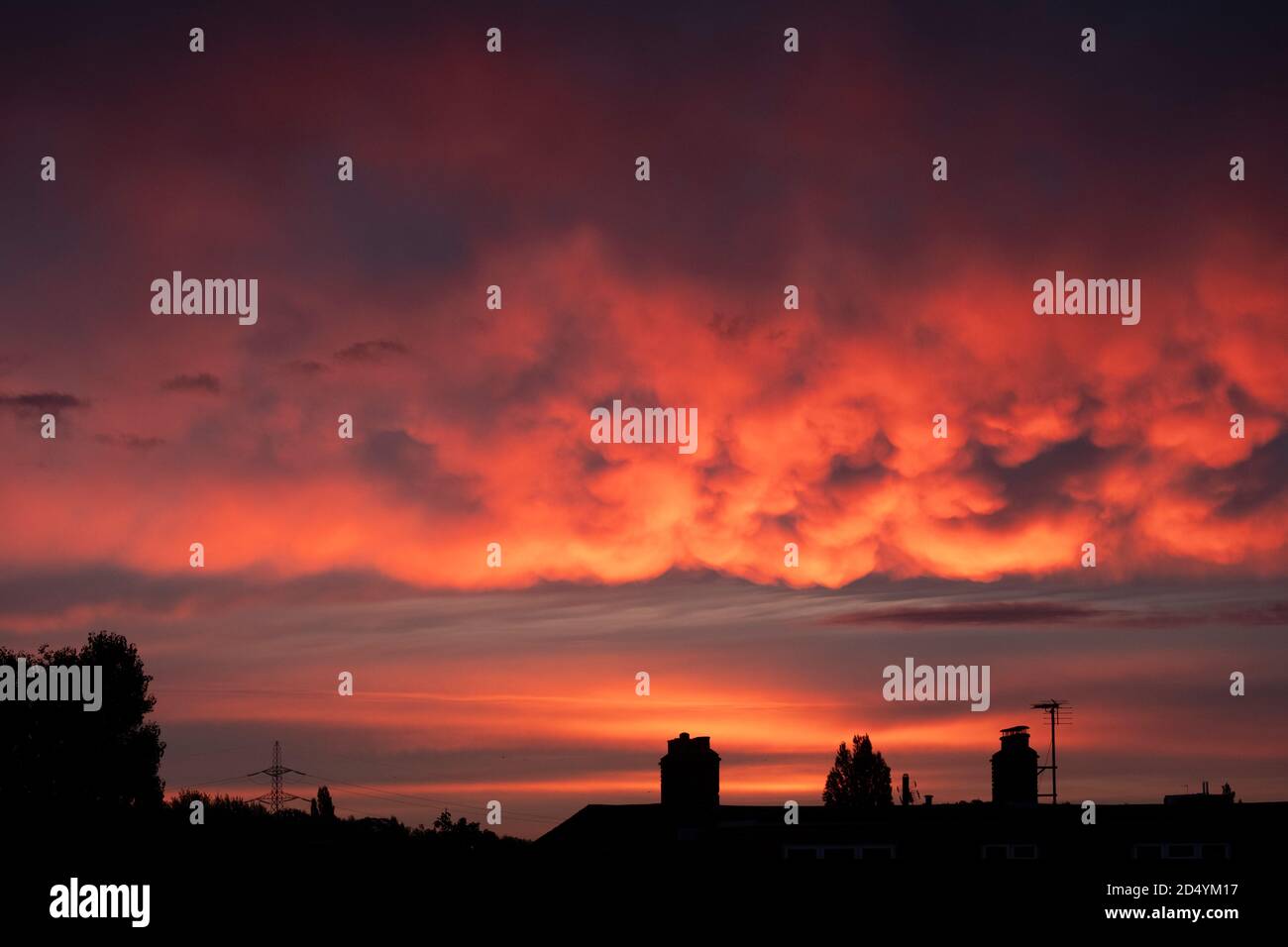 UK Weather: 12 October 2020. Dramatic and colourful clouds lit by the rising sun above rooftops in London SW19, UK Stock Photo