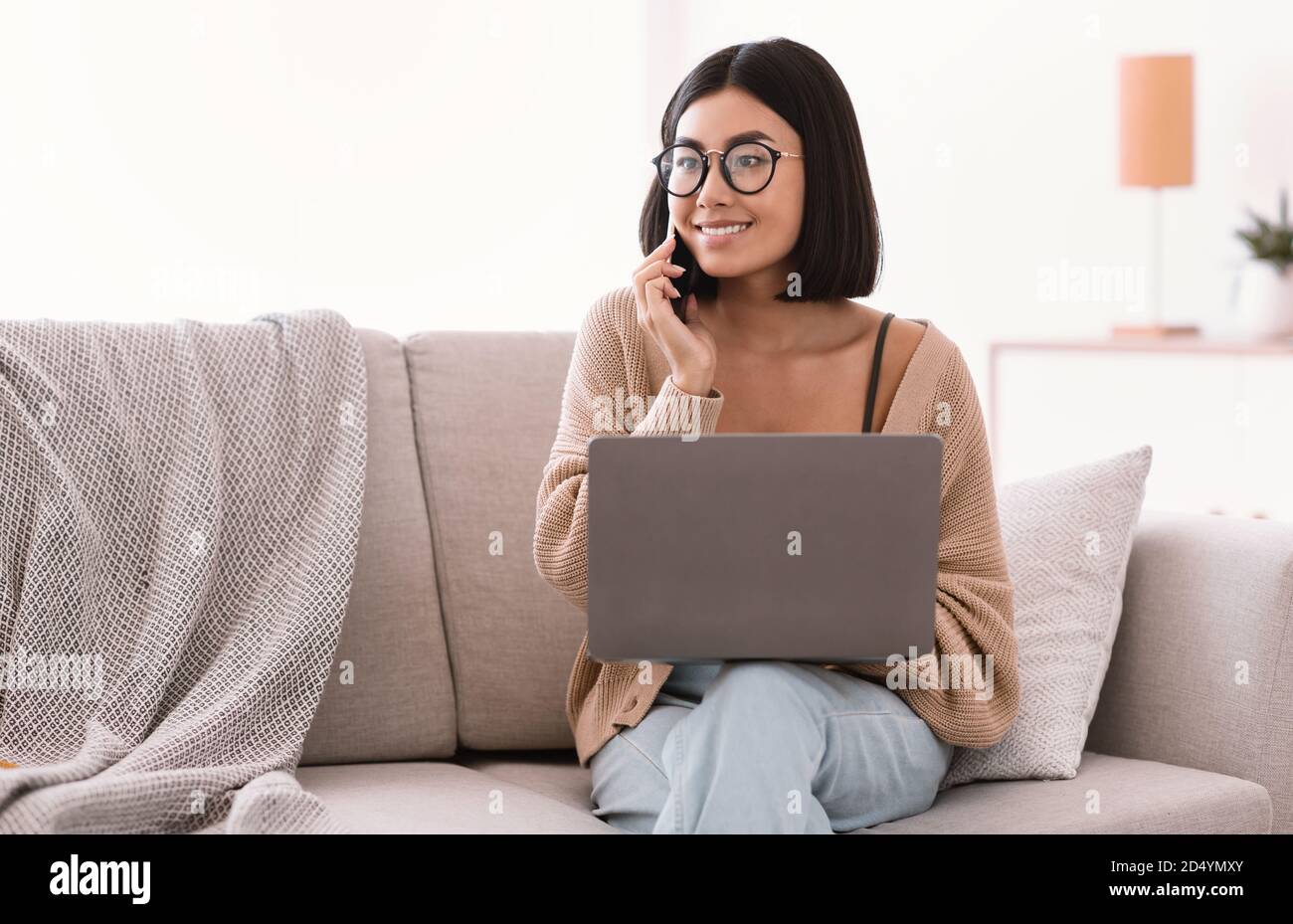 Portrait of smiling woman using pc talking on cellphone Stock Photo