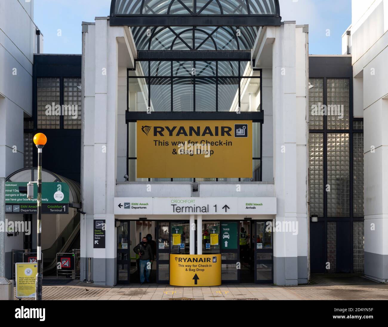Outdoor Ryanair advertisement and information sign at the empty entrance for the Dublin Airport Terminal 1 with only two passengers in sight in Dublin Stock Photo