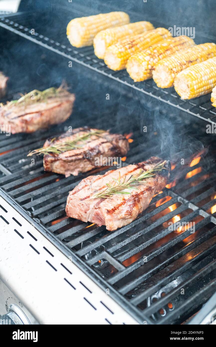 Grilling New York steak with a slice of butter and rosemary on an