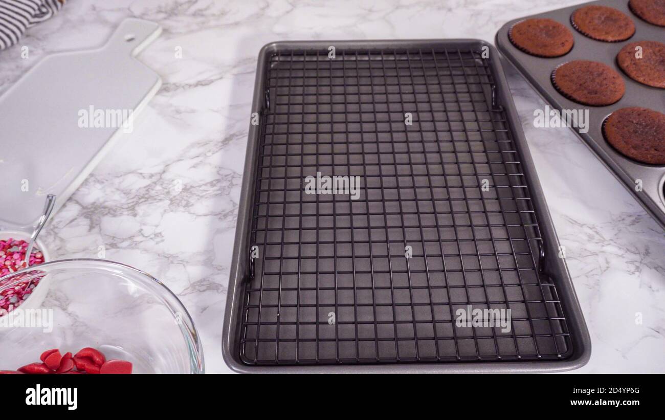 Step by step. Cooling red velvet cupcakes on a kitchen drying rack. Stock Photo