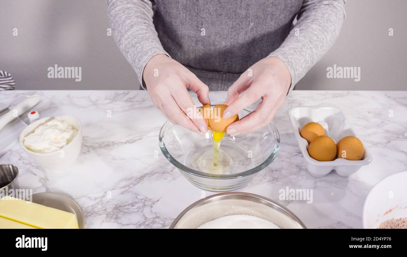 Step by step. Mixing wet ingredients in a glass mixing bowl to bake red velvet cupcakes Stock