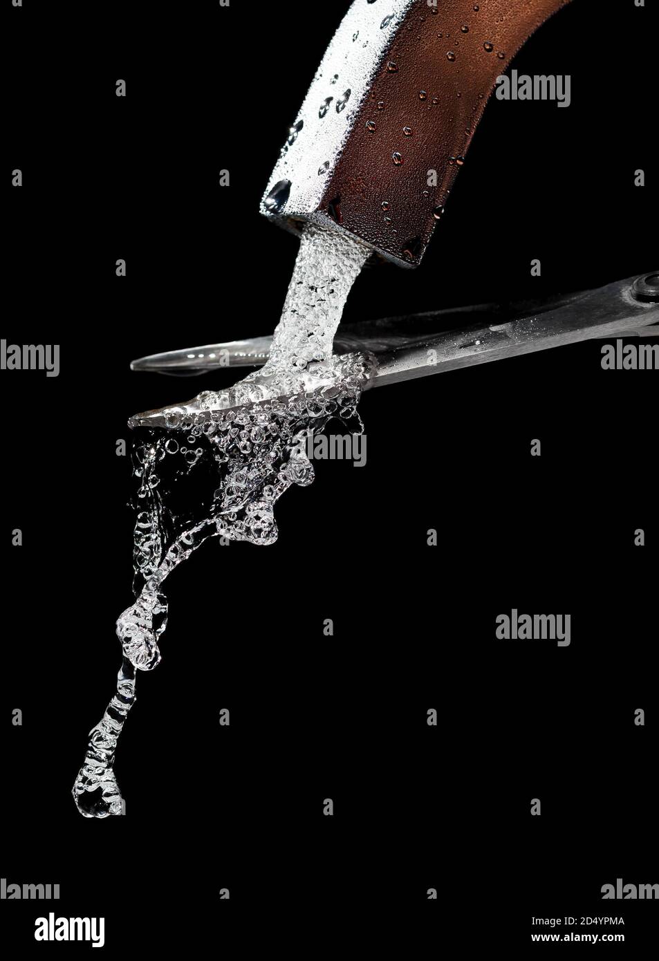 Scissors cut a stream of clean, cold water from a misted tap. Stock Photo
