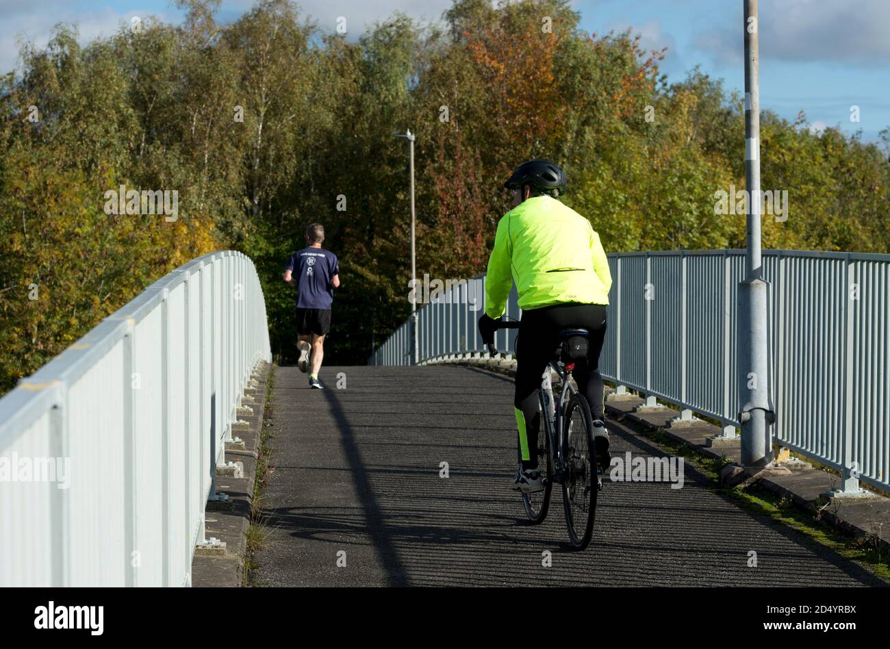 A runner and cyclist on a footbridge/cycleway near Warwick, Warwickshire, UK Stock Photo
