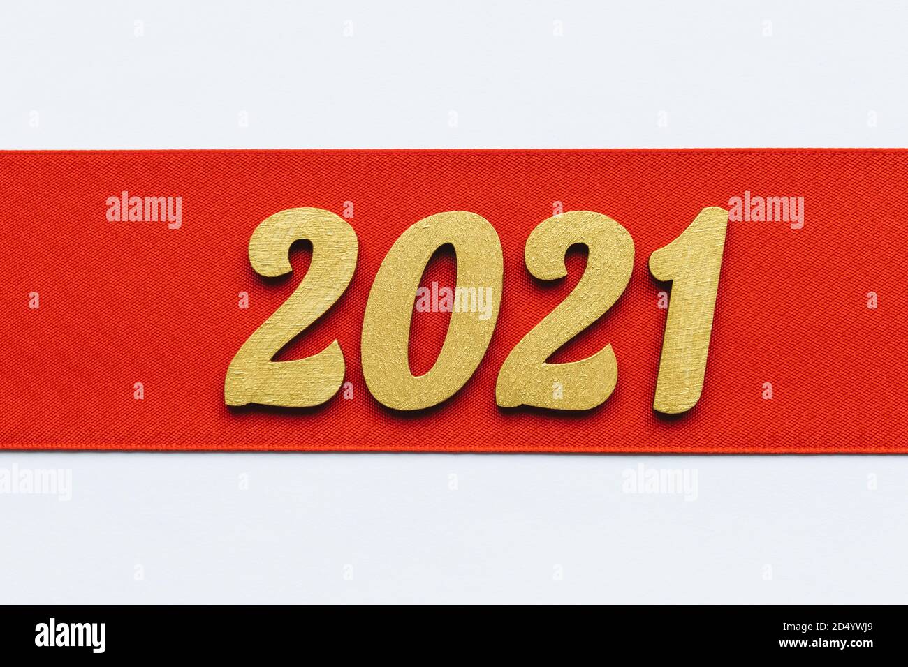 Festive background. Red ribbon with golden 2021 new year sign. Winter holiday celebration banner. Merry Christmas and Happy New Year. Space for text. Stock Photo