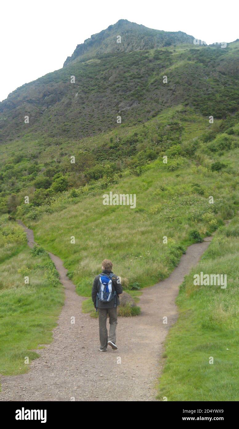 Man hiking through the scottish highlands. This fork in the road leads him into different directions Stock Photo