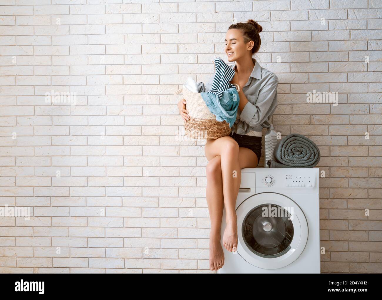 Beautiful young woman is smiling while doing laundry at home Stock ...