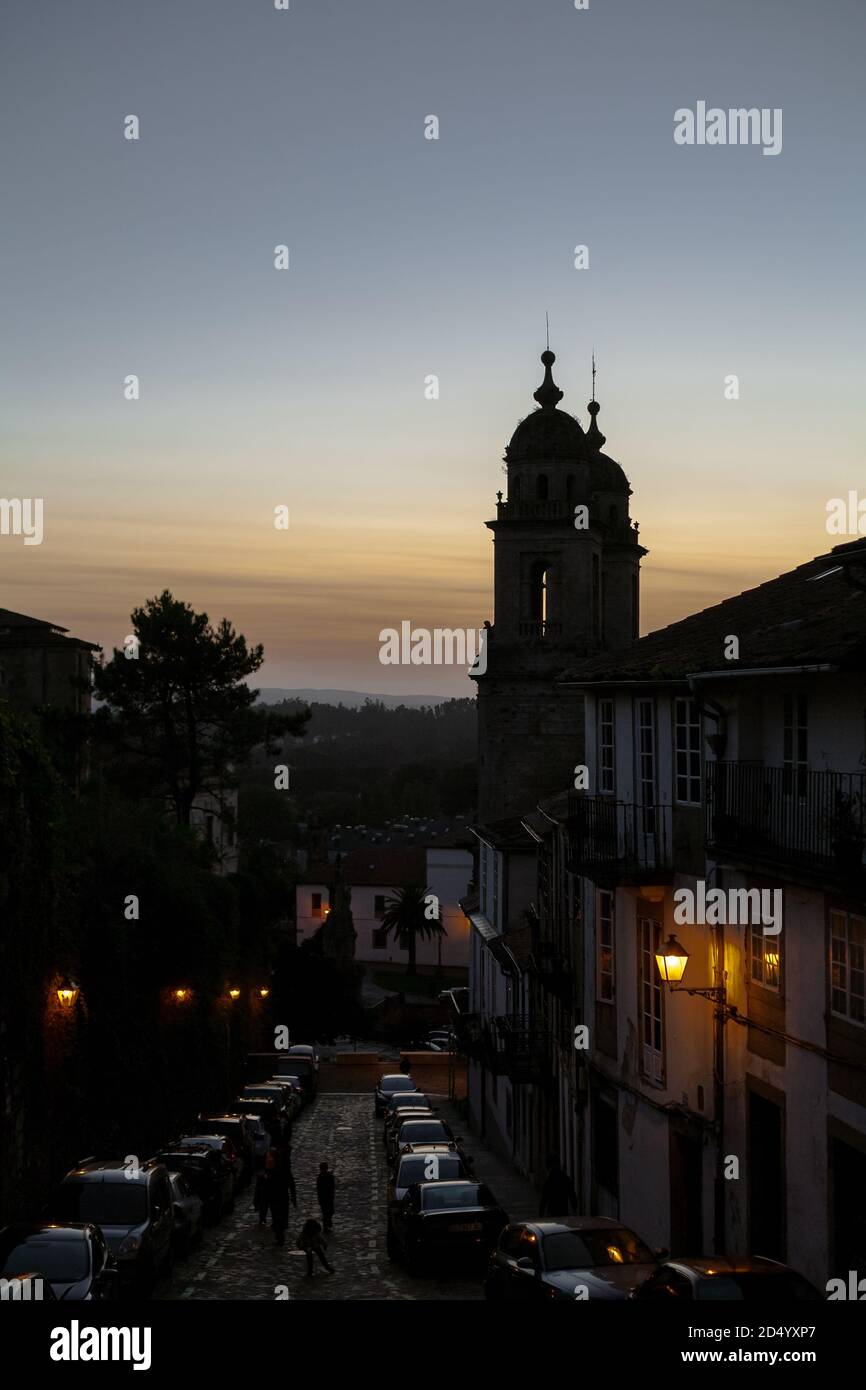 Santiago de Compostela, Galicia, Spain - 09/27/2020: Convento de San Francisco at sunset with a dimly sit street in front as people walk up it. Spain Stock Photo
