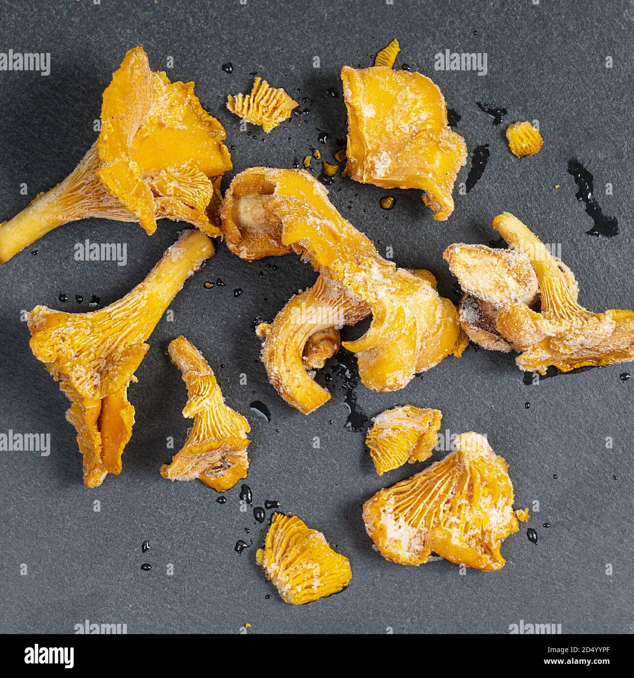 Some frozen chanterelle,  Cantharellus cibarius,  mushrooms on a black surface Stock Photo