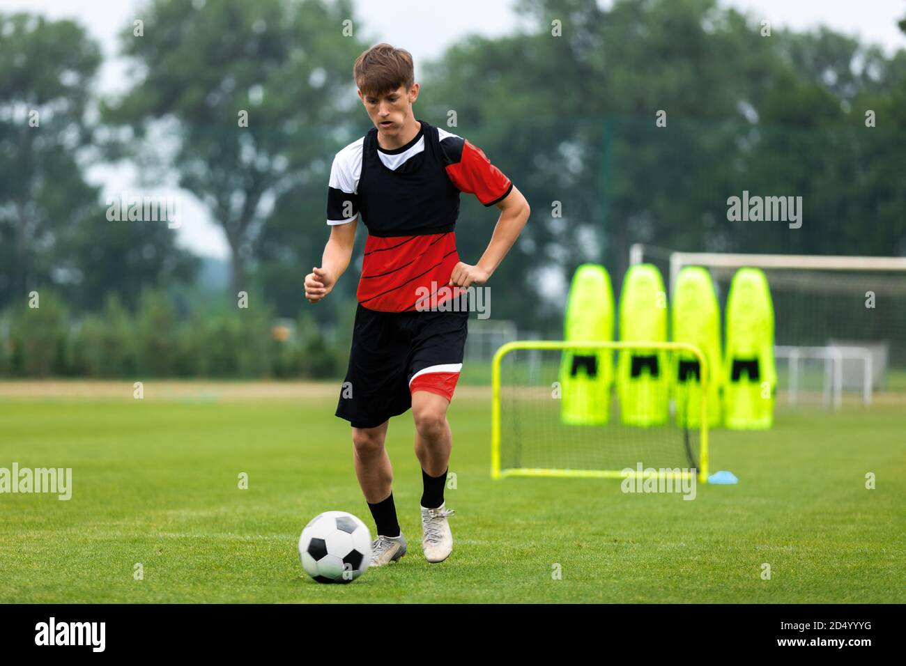 Youth Soccer Training. Young Player on Drills, Exercises And Match Preparation Training Session. Soccer Player Running With Ball. Training Goal and Fo Stock Photo