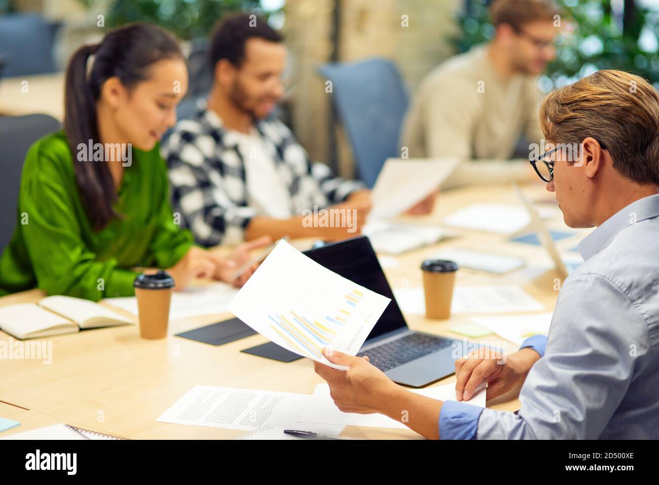 Brainstorming meeting. Group of multiracial people sitting at the desk in the modern coworking space or office and working on project together. Teamwork and collaboration, business concept Stock Photo