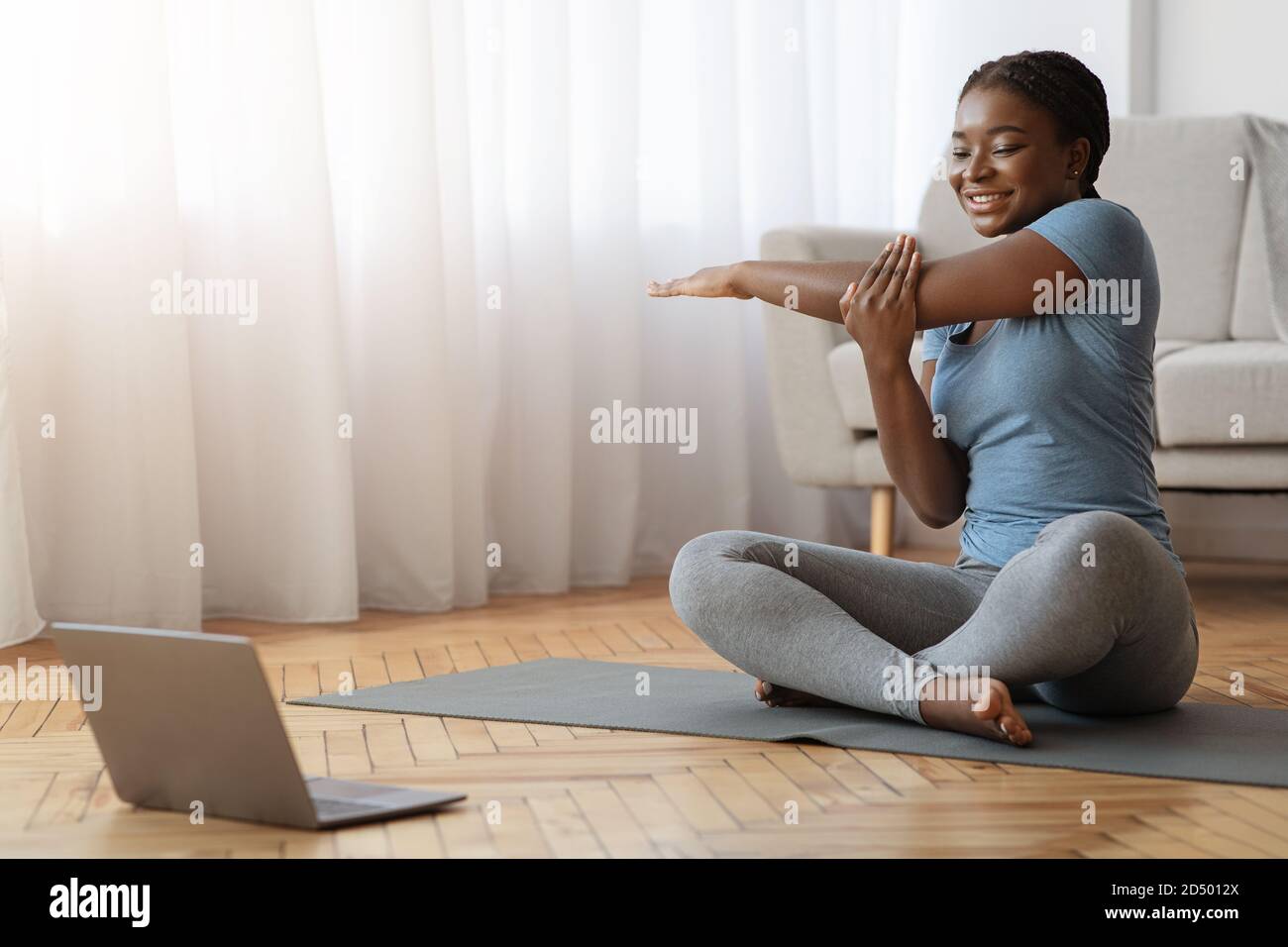 Cheerful African Woman Stretching Up In Front Of Laptop, Doing Home Workout Stock Photo